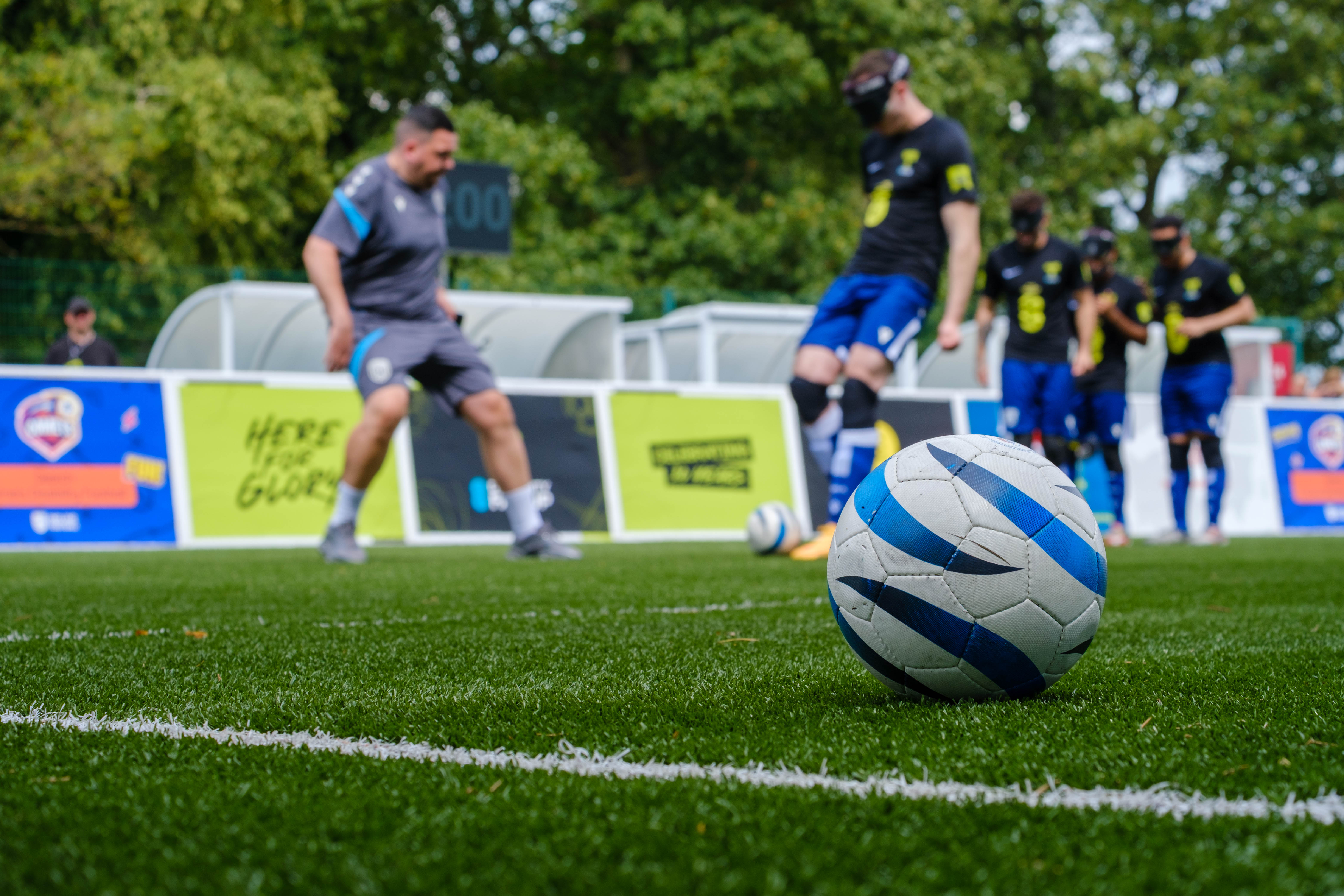 Close-up of ball with WBA Blind players warming up in the background.