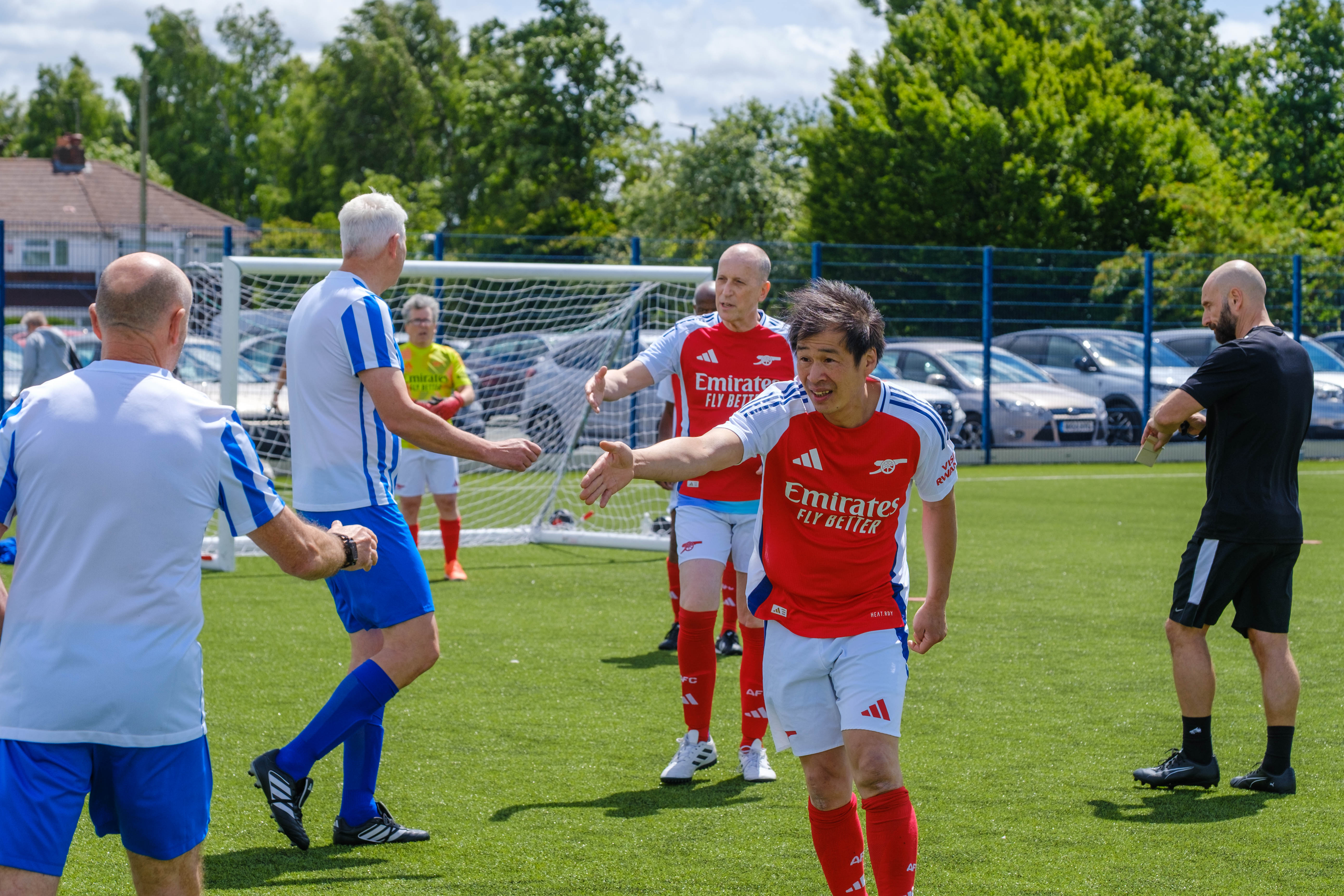 Arsenal players reaching out for a hand shakes with Movers and Shakers players 