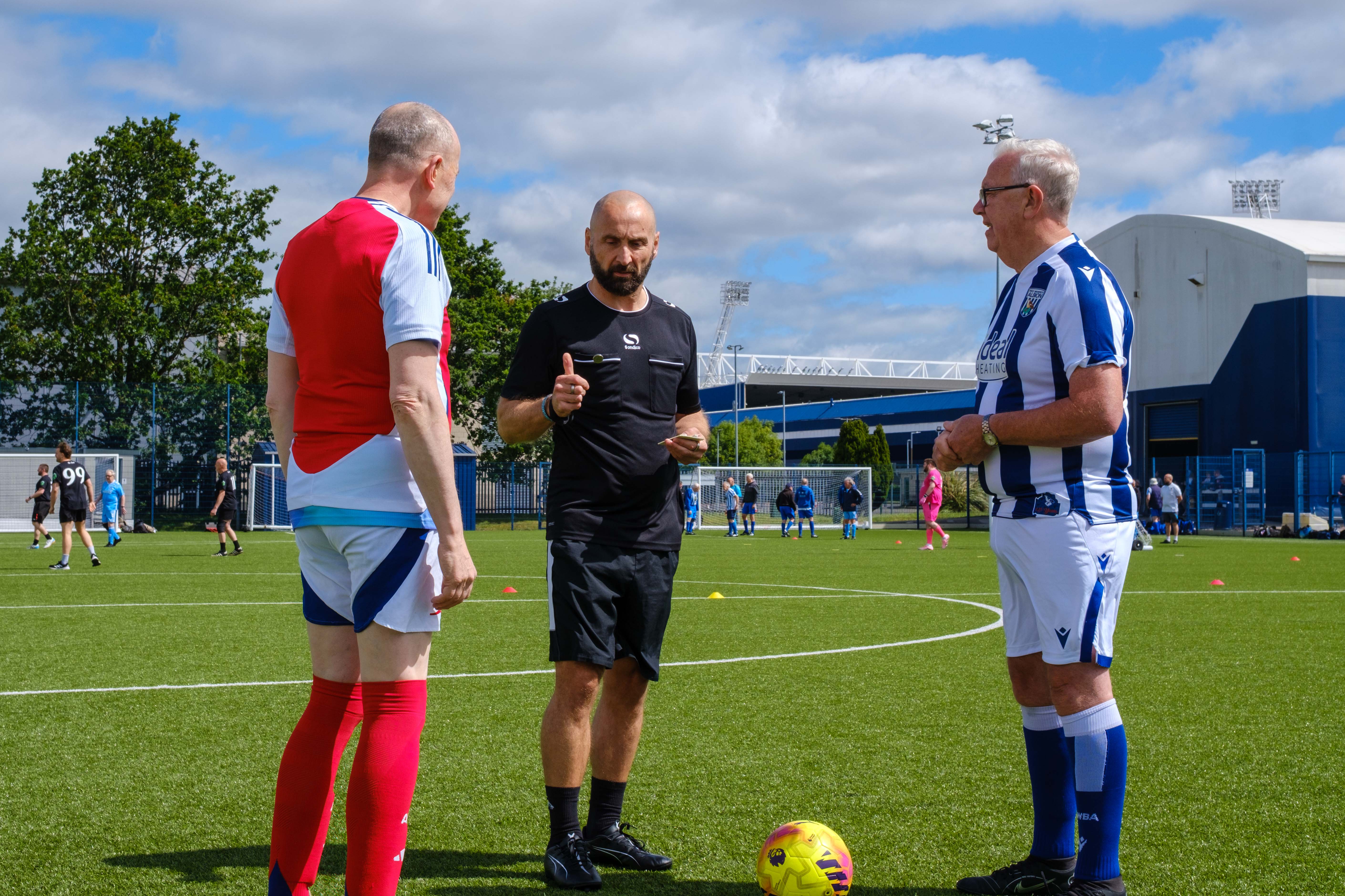 Arsenal and Cancer Kickers captains with referee discussing coin toss.