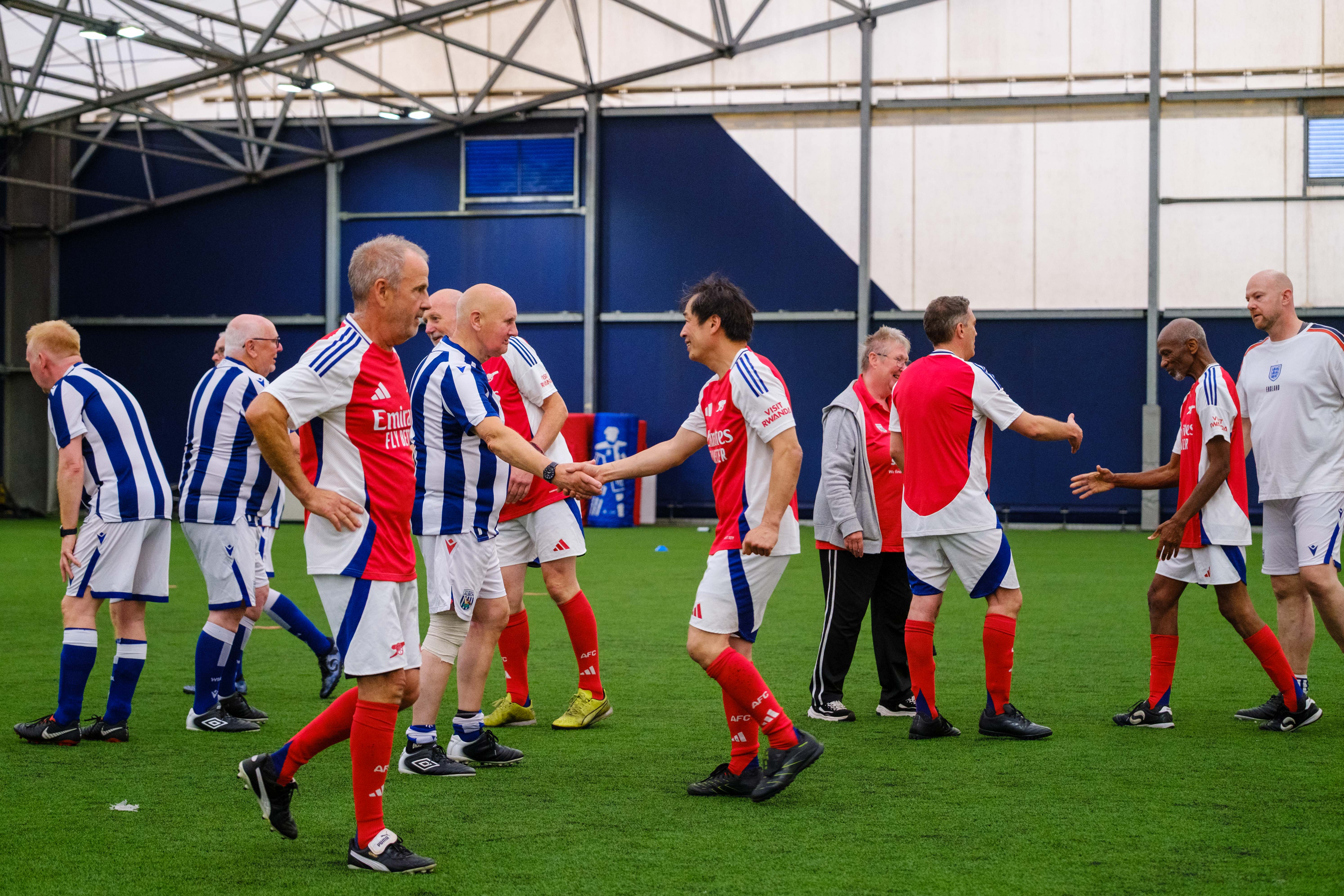 Arsenal and Cancer Kickers shaking hands after the game.
