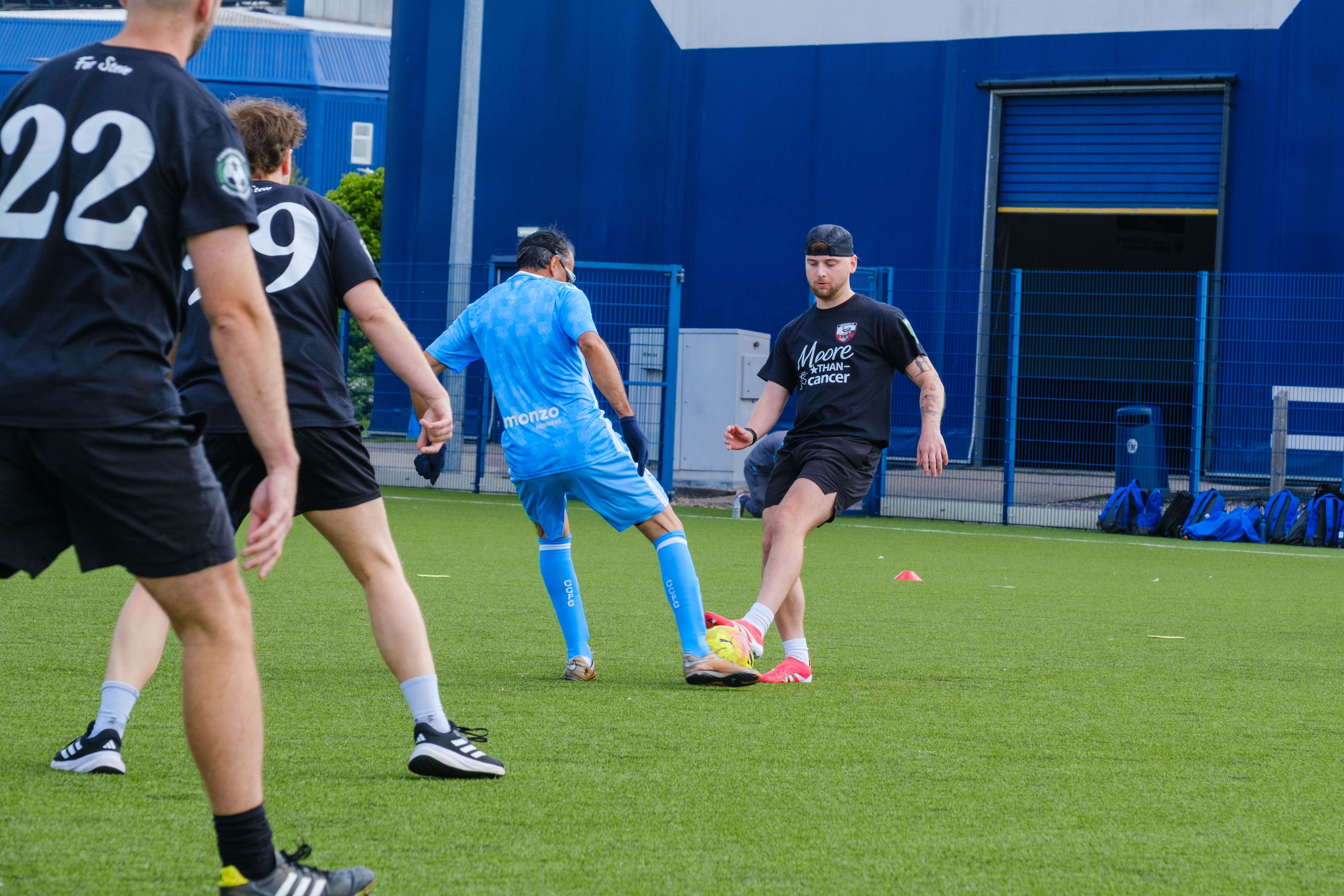 Sky Blue in the Community and Moore than Cancer player challenging for the same ball.