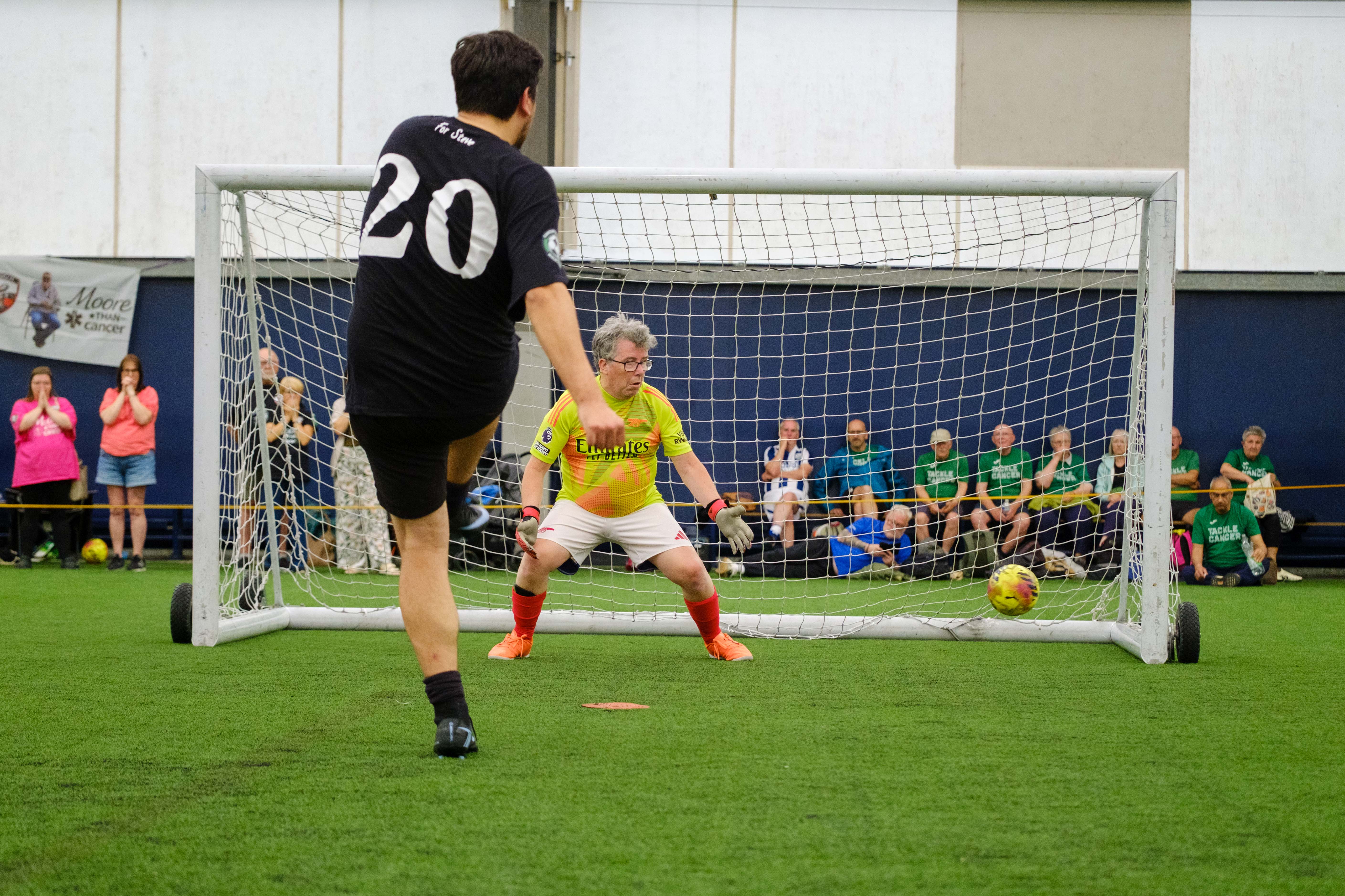 Moore than Cancer player striking his penalty with Arsenal goalkeeper attempting to dive for it.