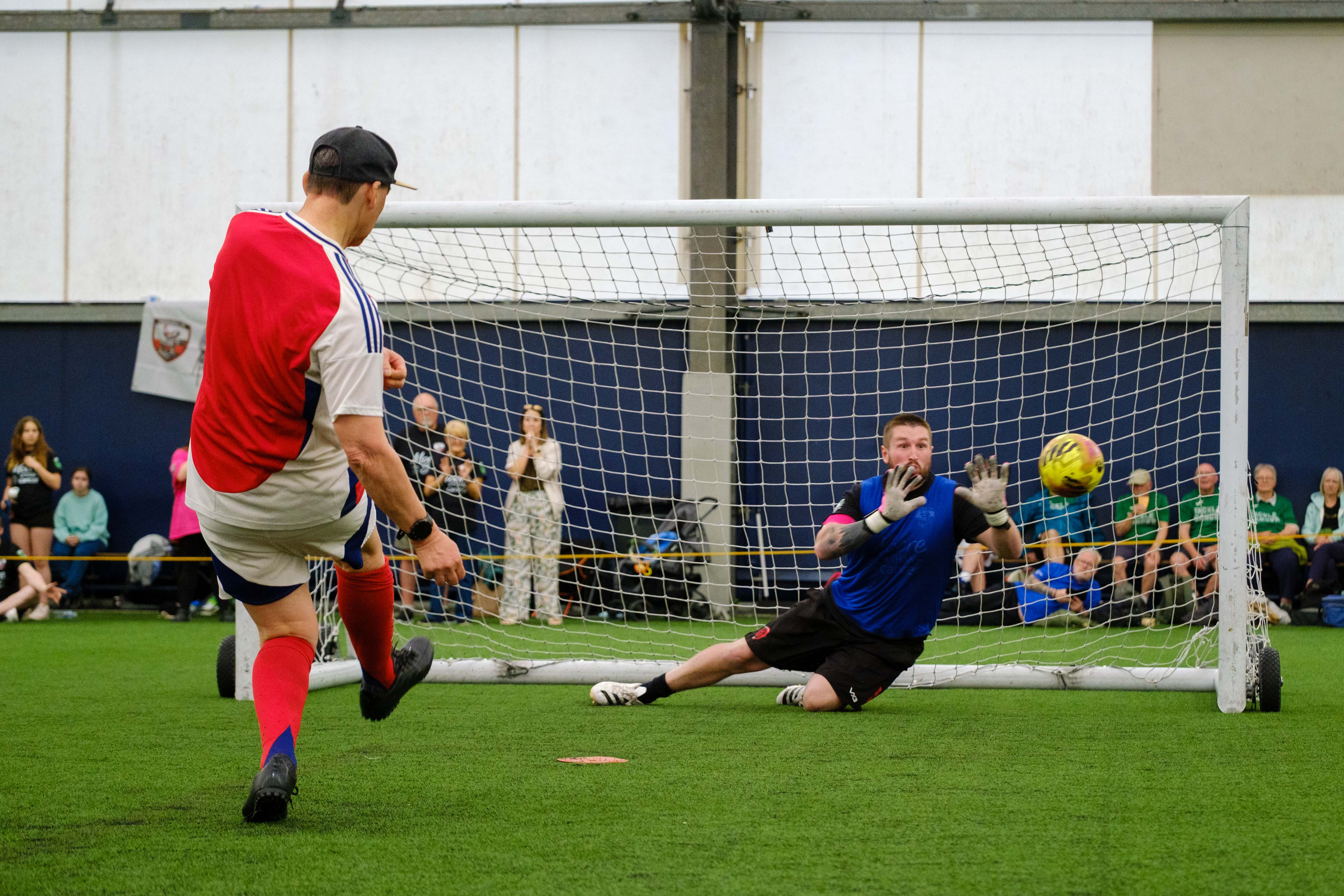 Arsenal player striking his penalty with Moore than Cancer goalkeeper attempting to save it.