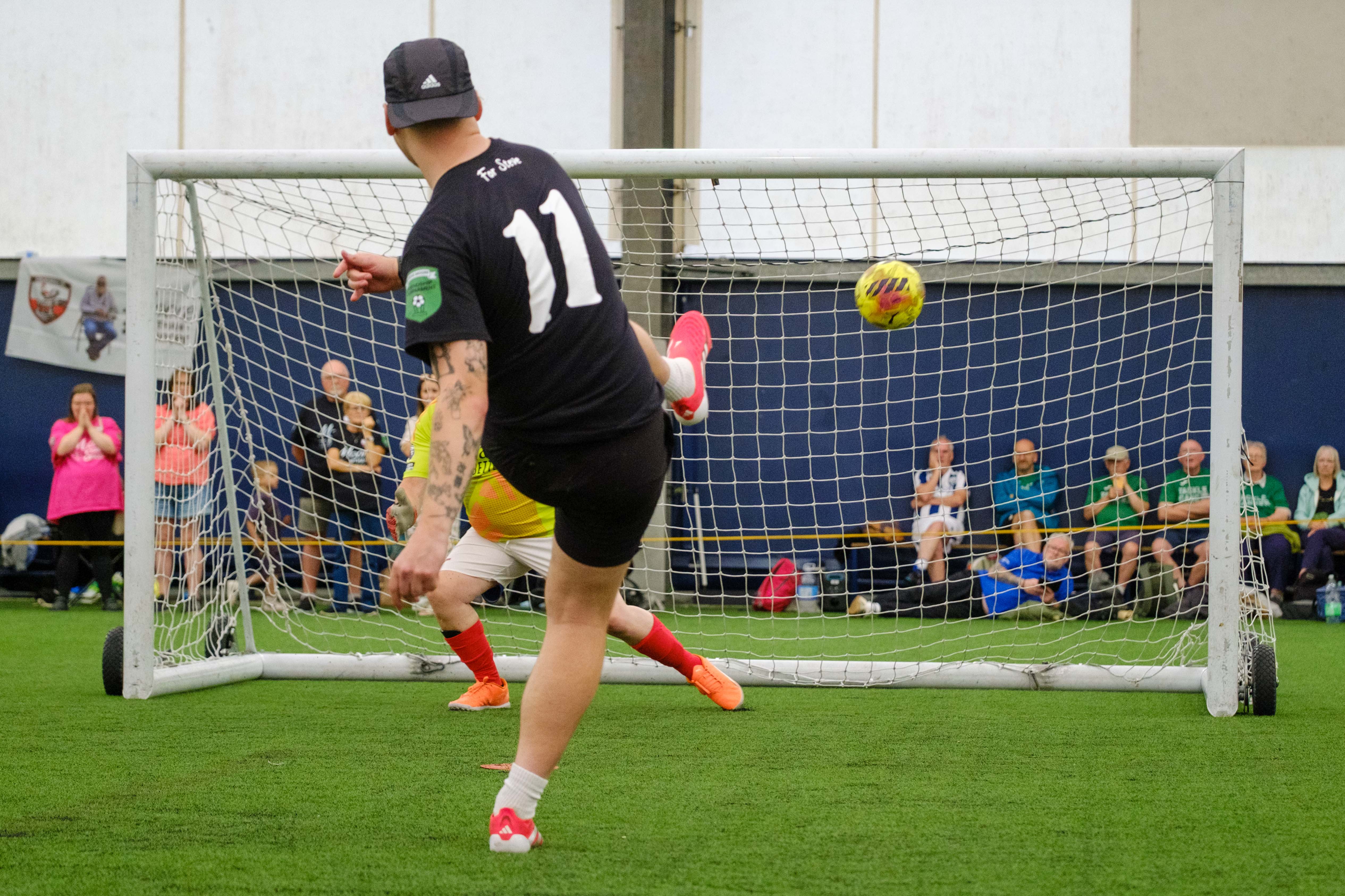 Moore than Cancer player striking his penalty with Arsenal goalkeeper diving the opposite way.