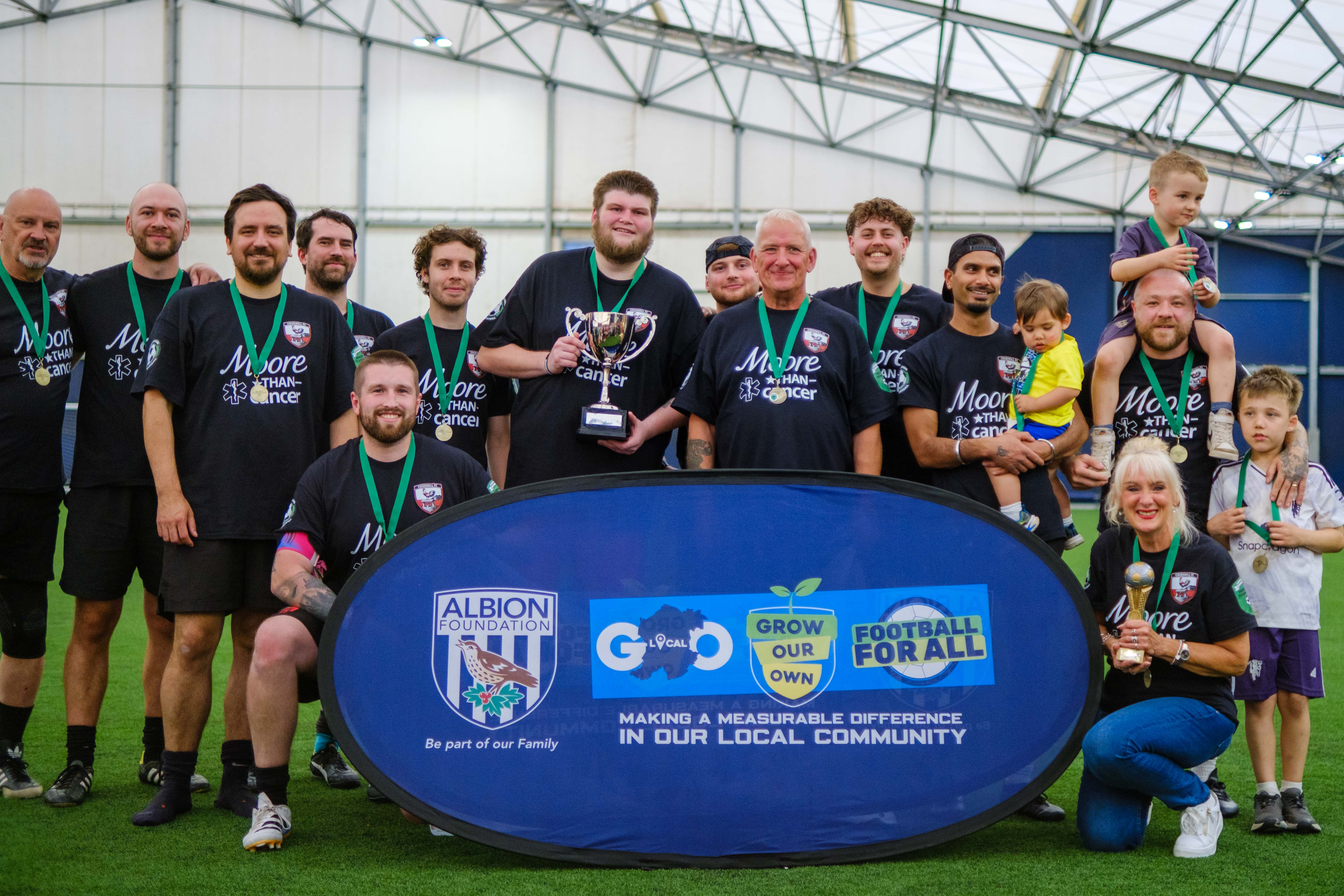 Moore than Cancer with trophy in front of Albion Foundation branded banner.