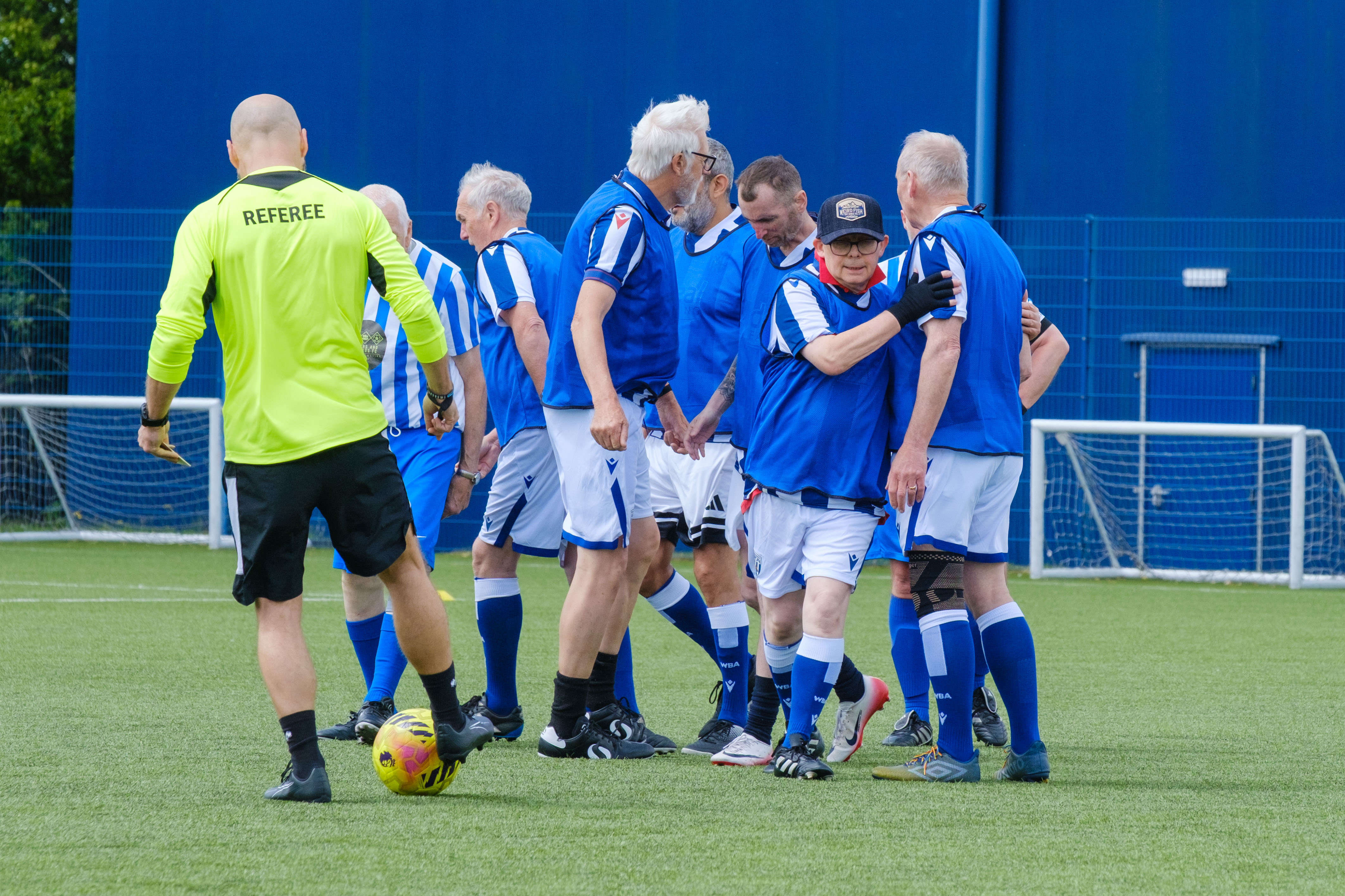 Close-up of Cancer Kickers players in blue bibs, celebrating a goal
