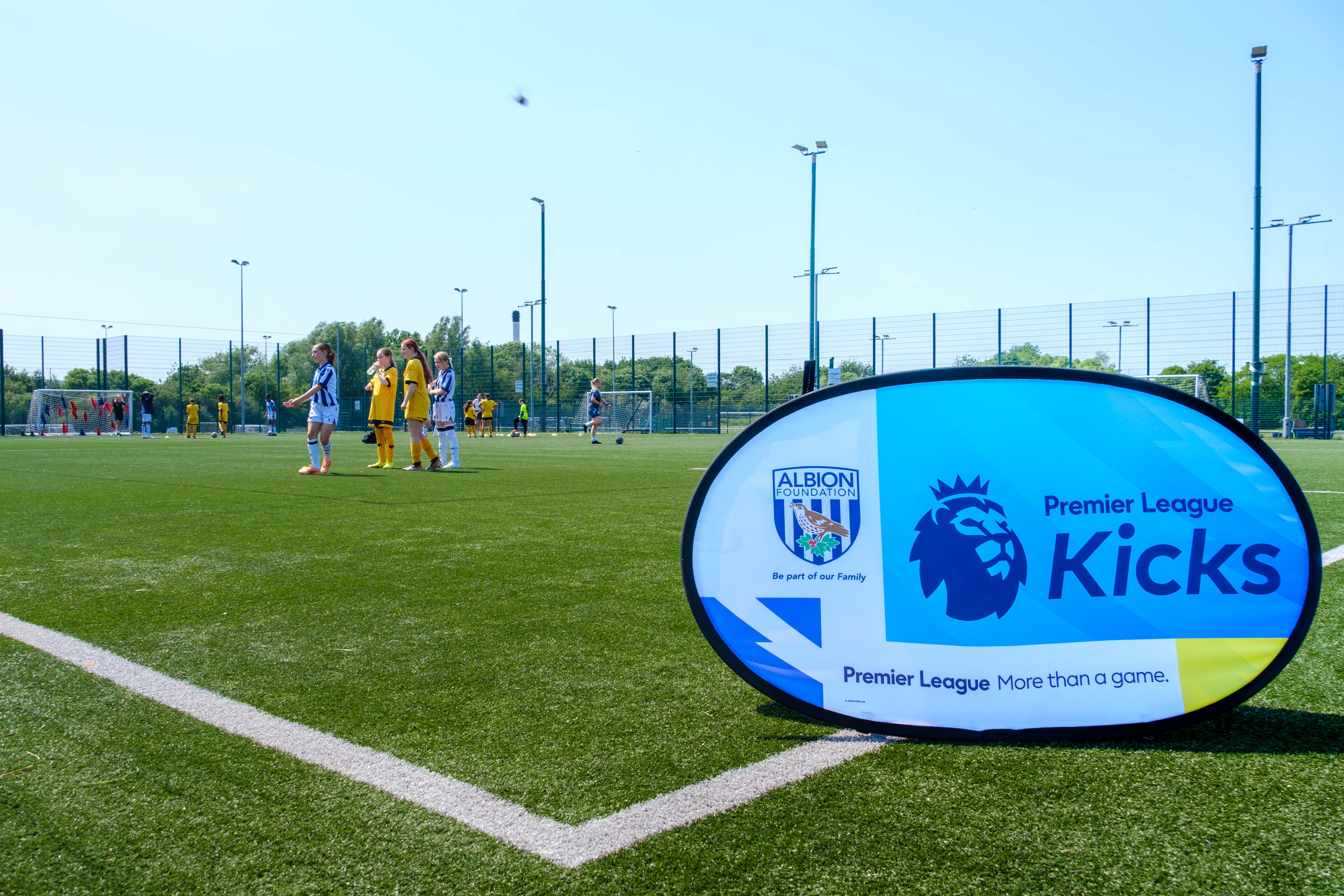 PL Kicks sign with participants in the background