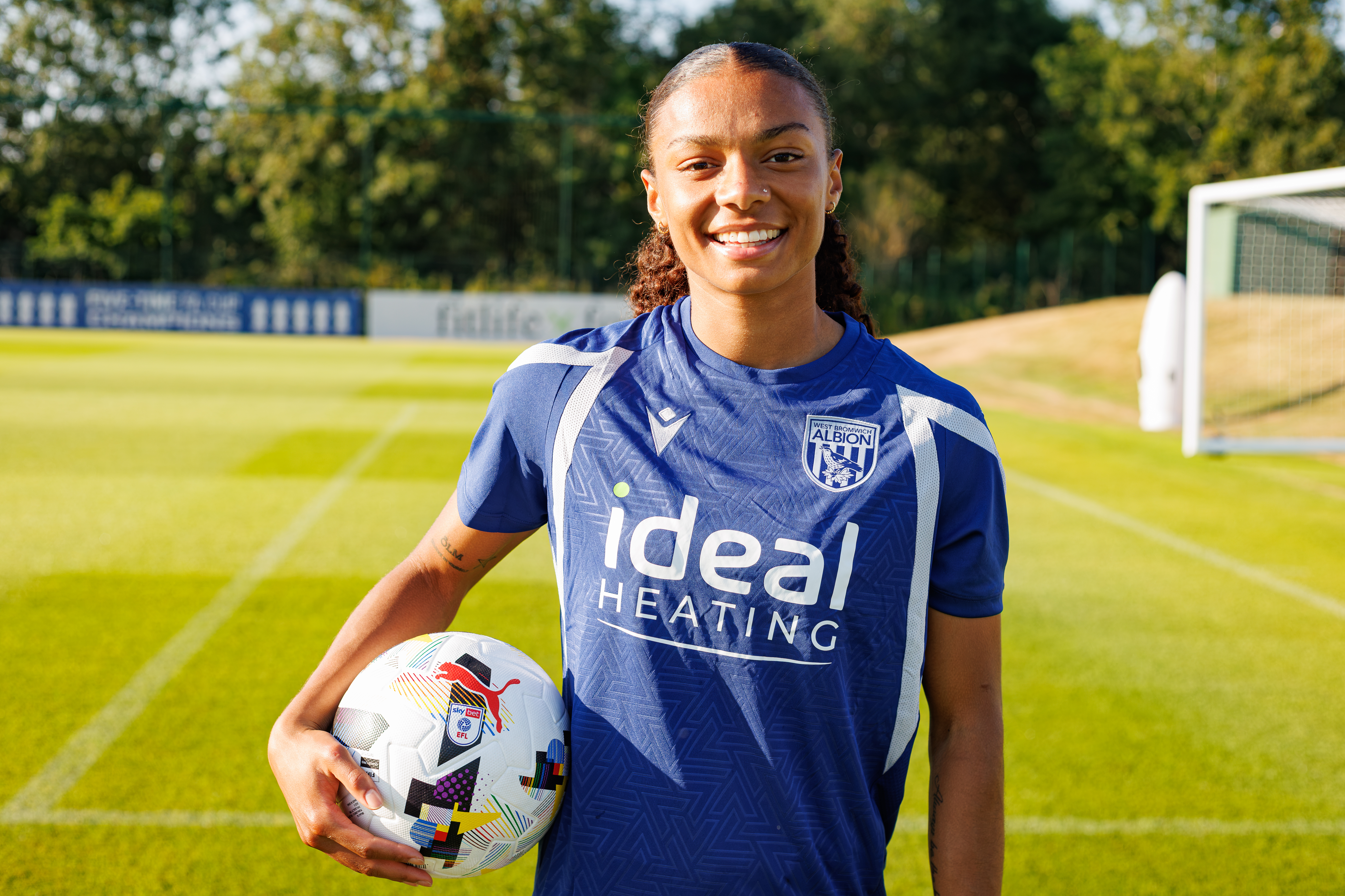 Izzy Lane holds a football and smiles at the camera