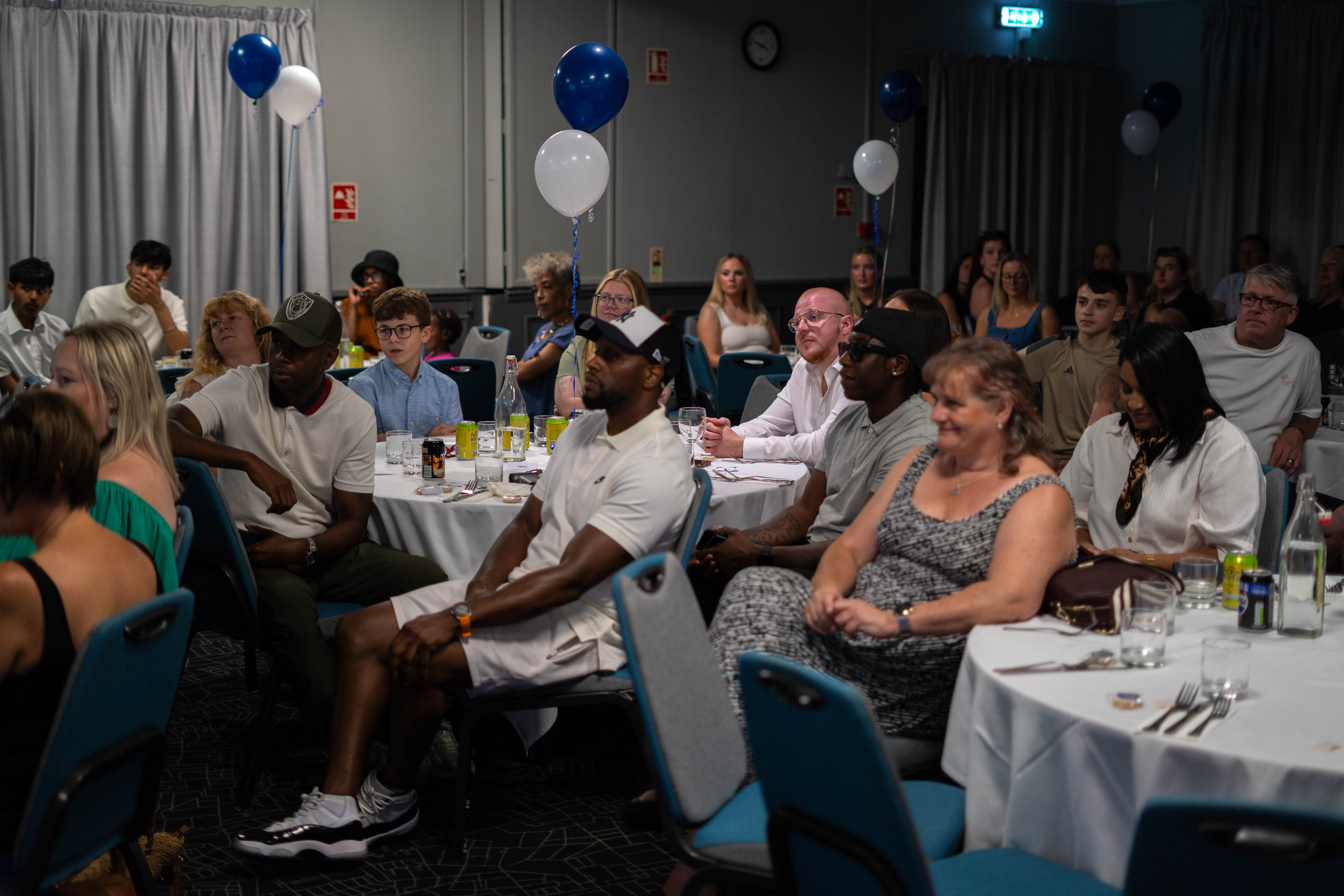 Guests seated at their tables, listening intensely.