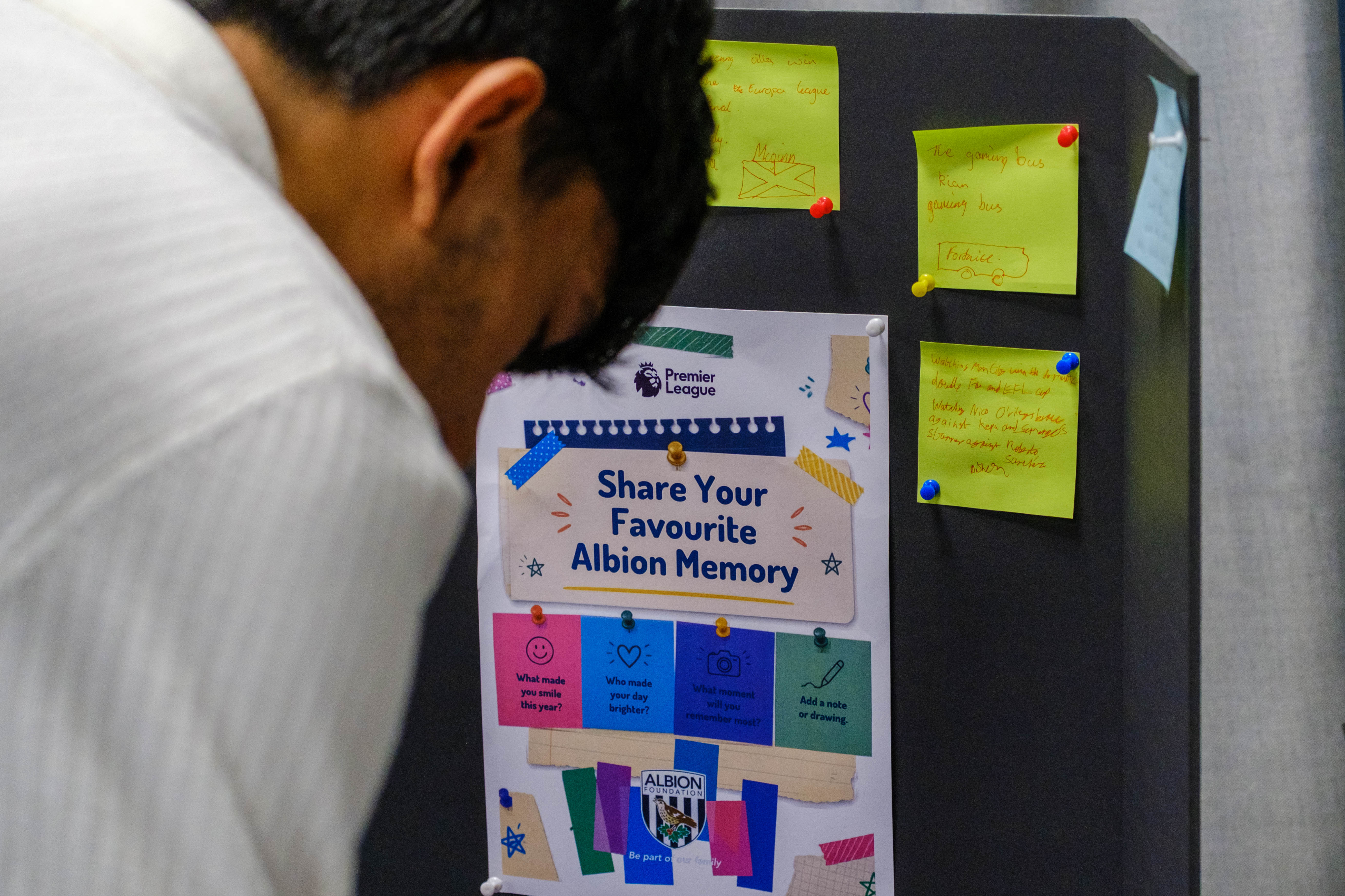Participant writing on a post-it to pin on Foundation Memories board.