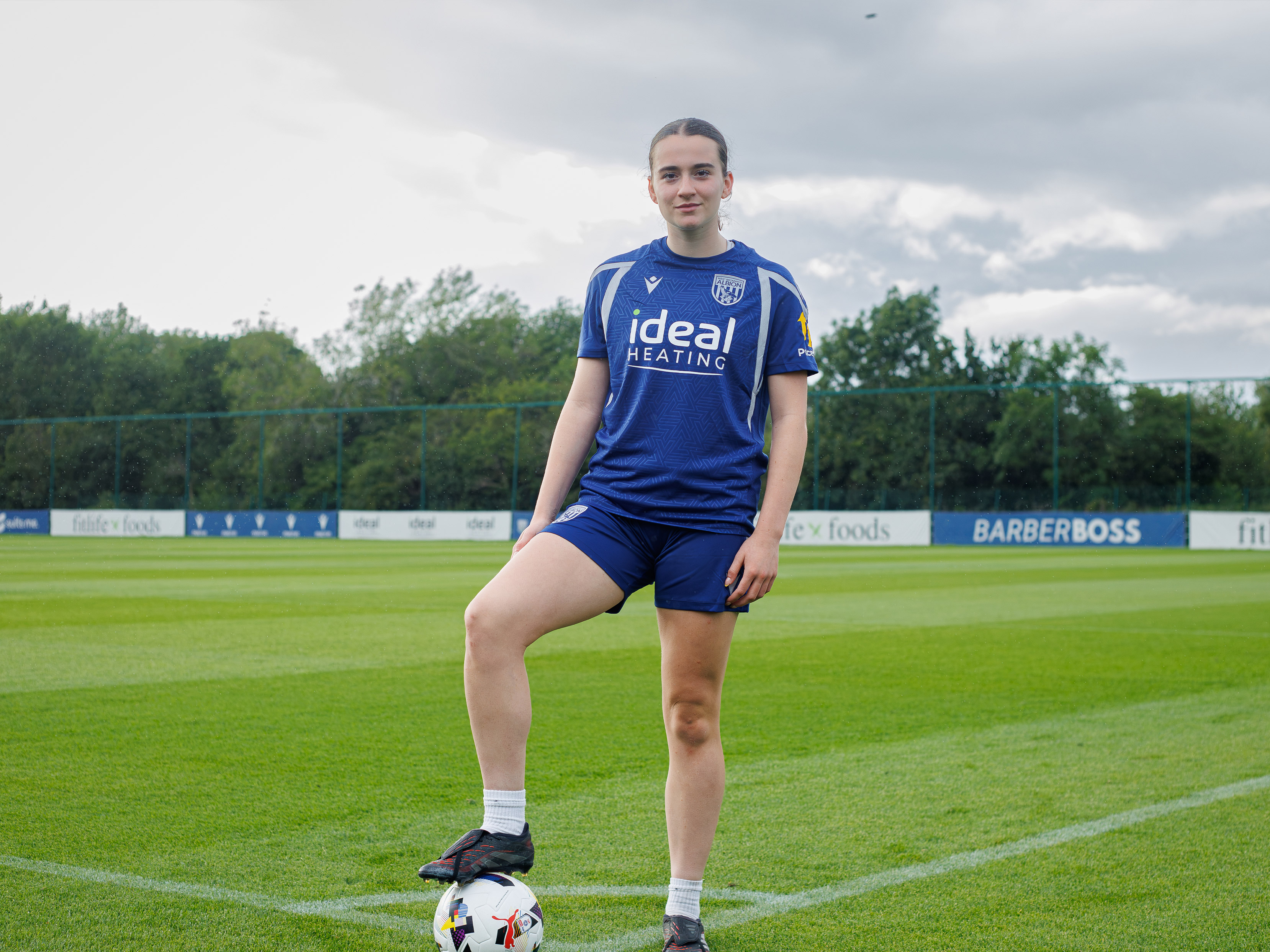 Lucy Day poses with her foot on a football.