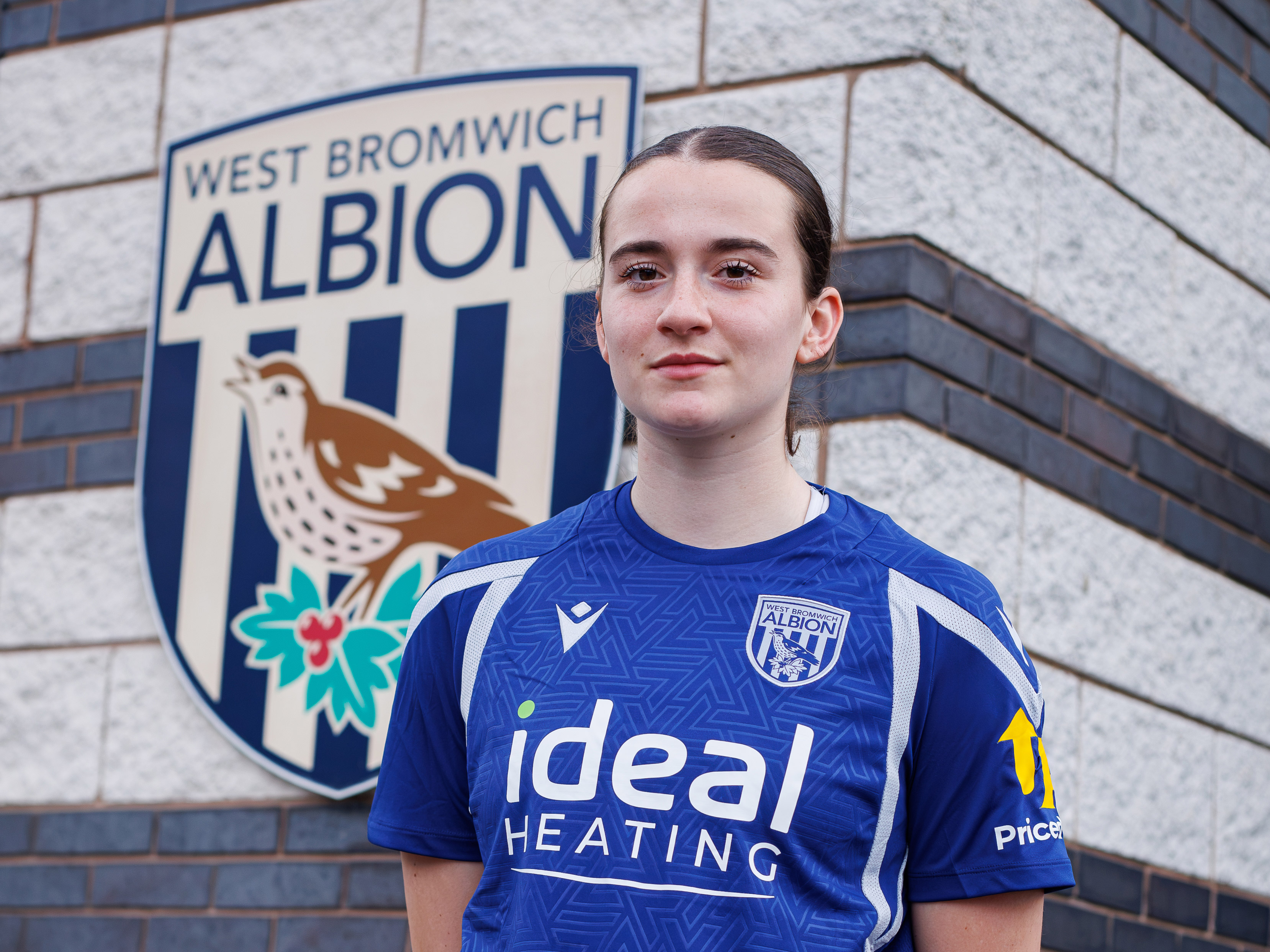 Lucy Day poses in front of a big Albion badge.