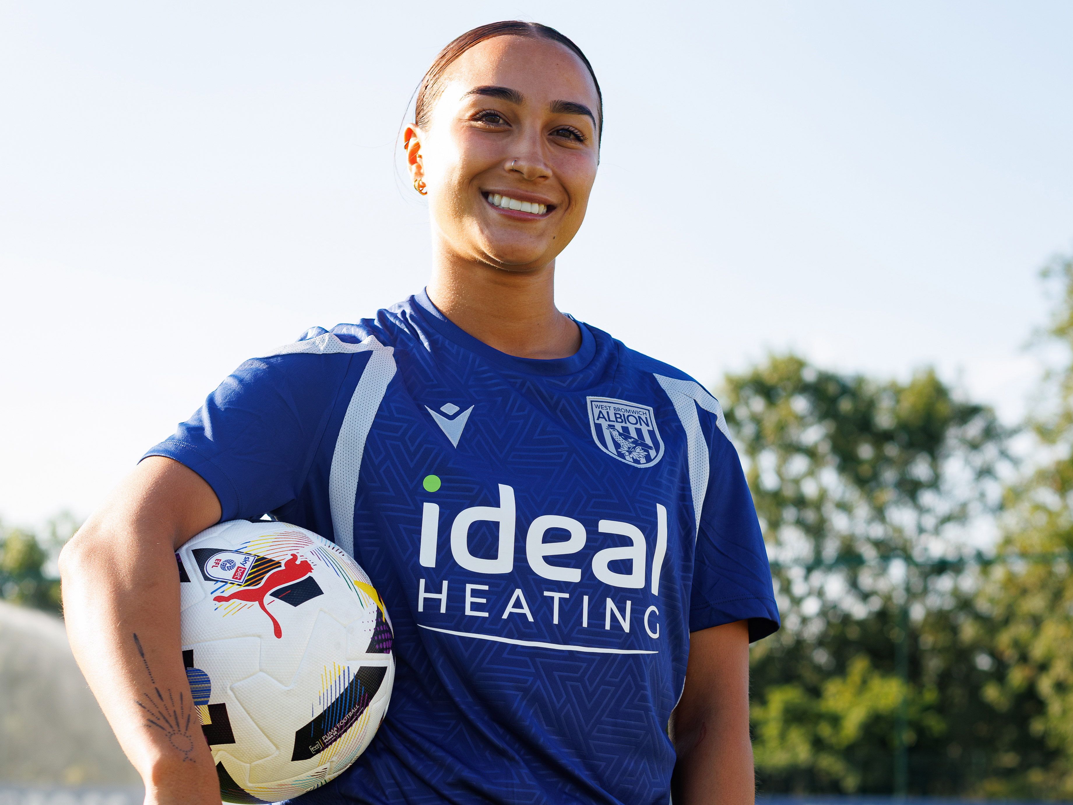 Rhianne Rush holds a football and smiles at the camera