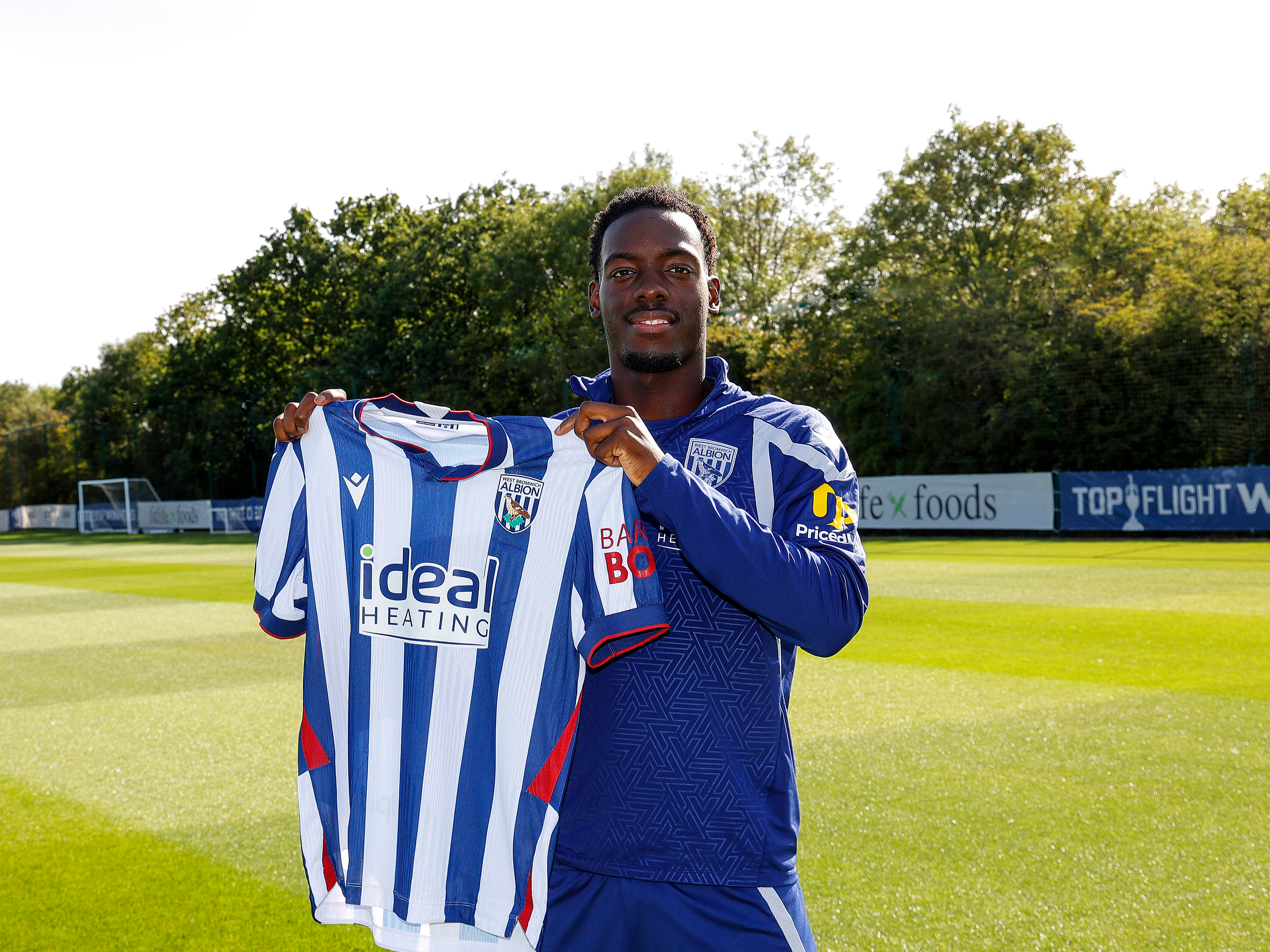 Rabby Nzingoula holding up an Albion home shirt.