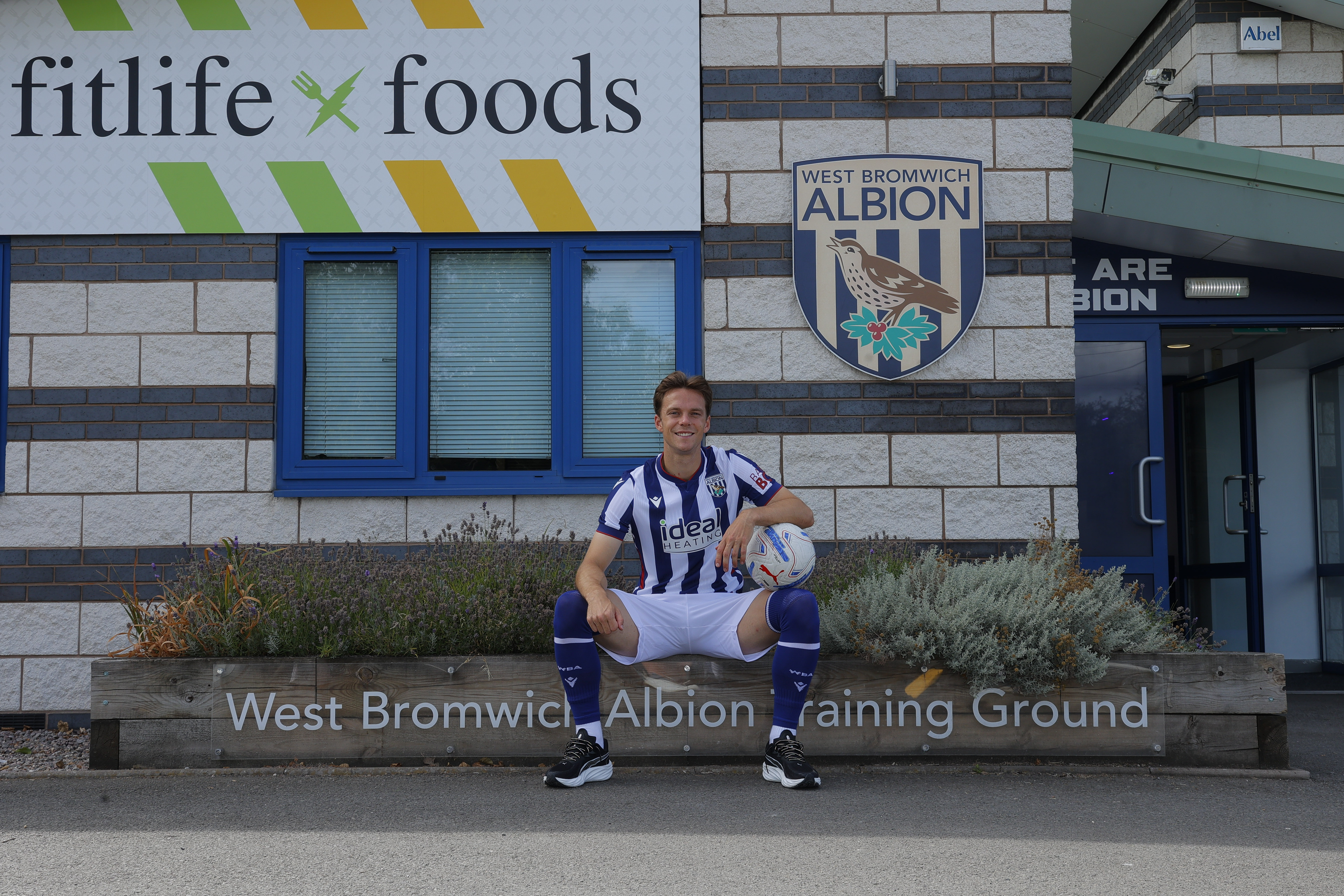 Felix Horn Myhre sat outside the training ground in the home kit smiling at the camera while holding a ball