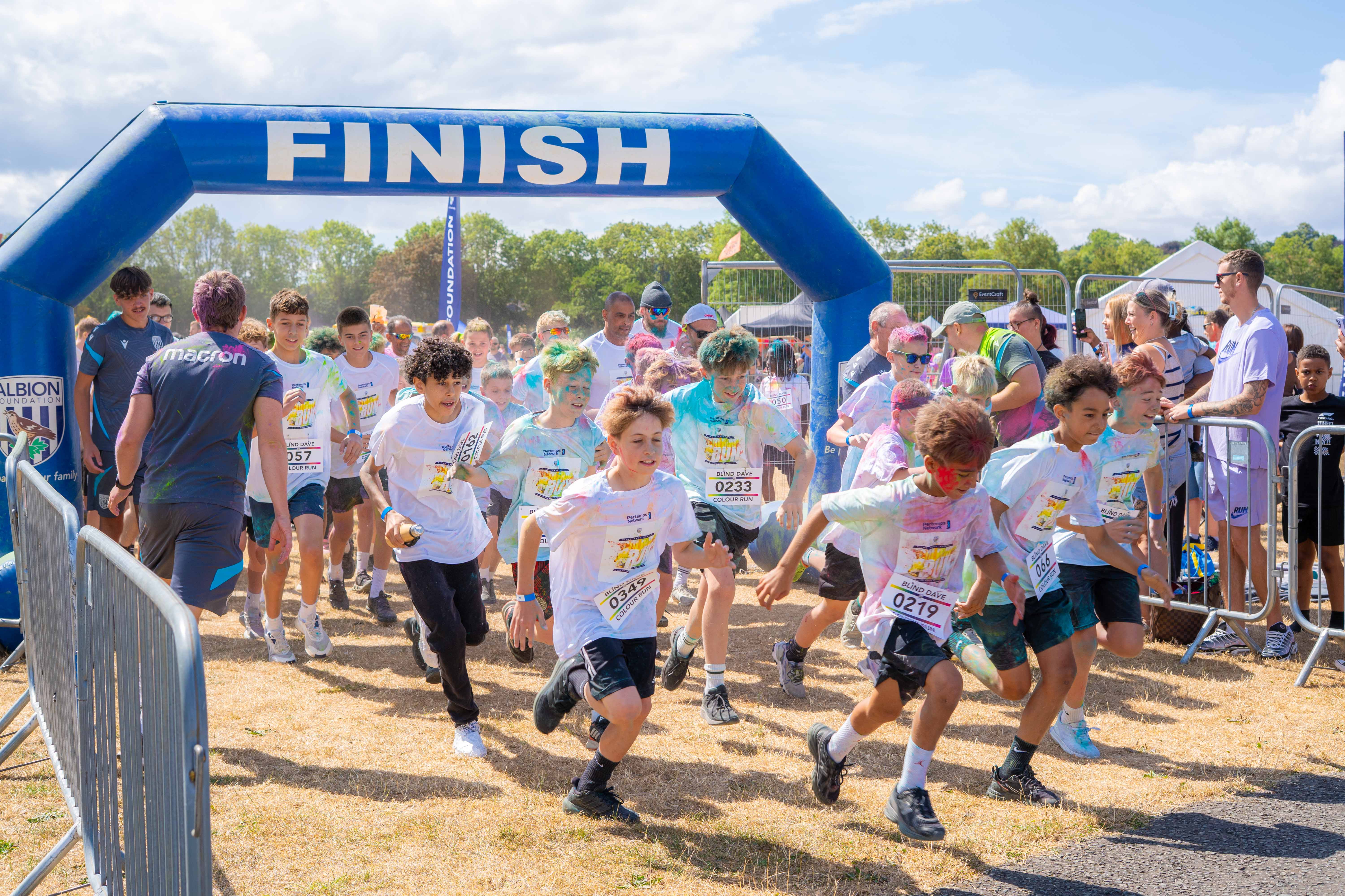 Participants run through a start line arch at a colour run event.