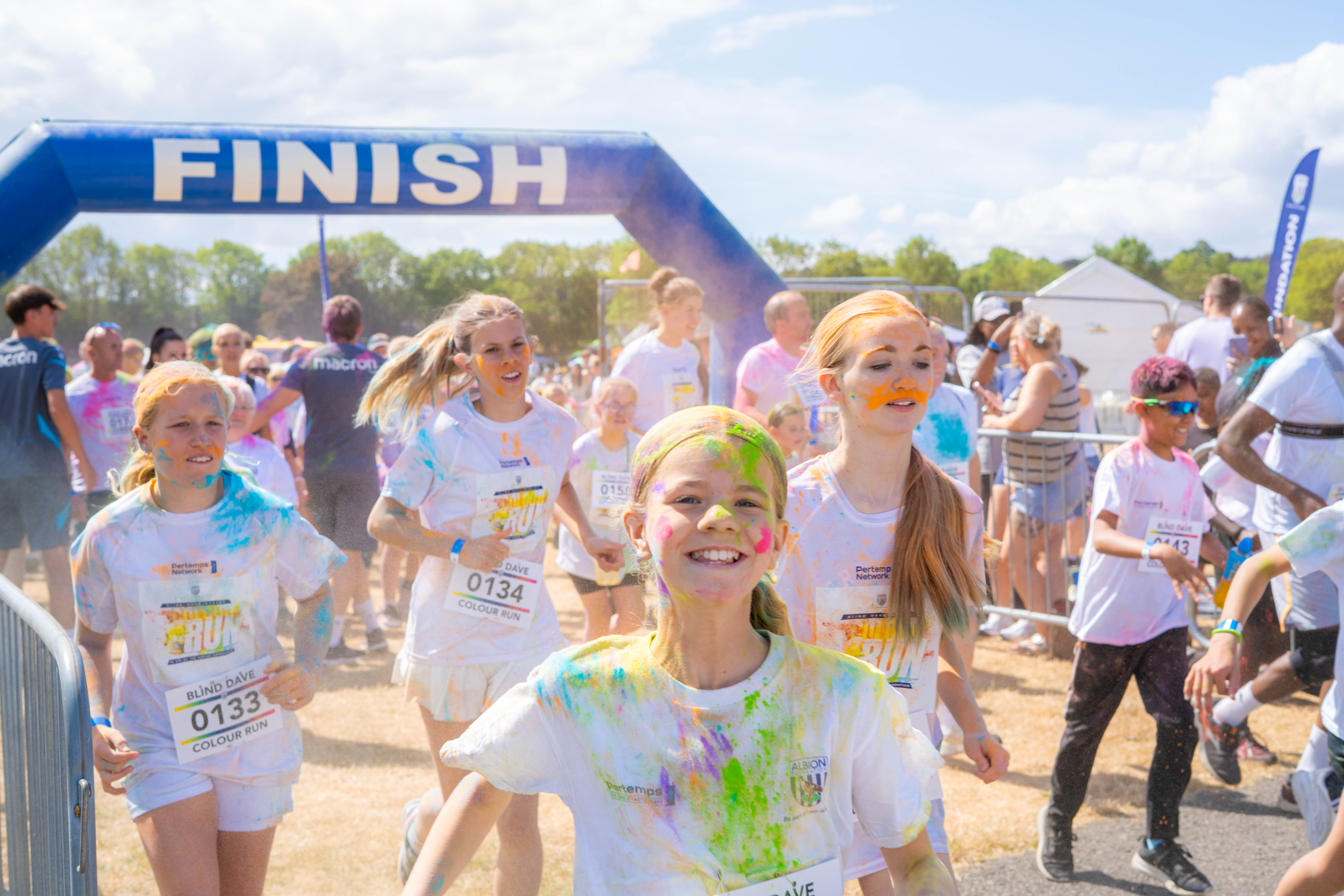 Participants covered in coloured powder run at the start line.