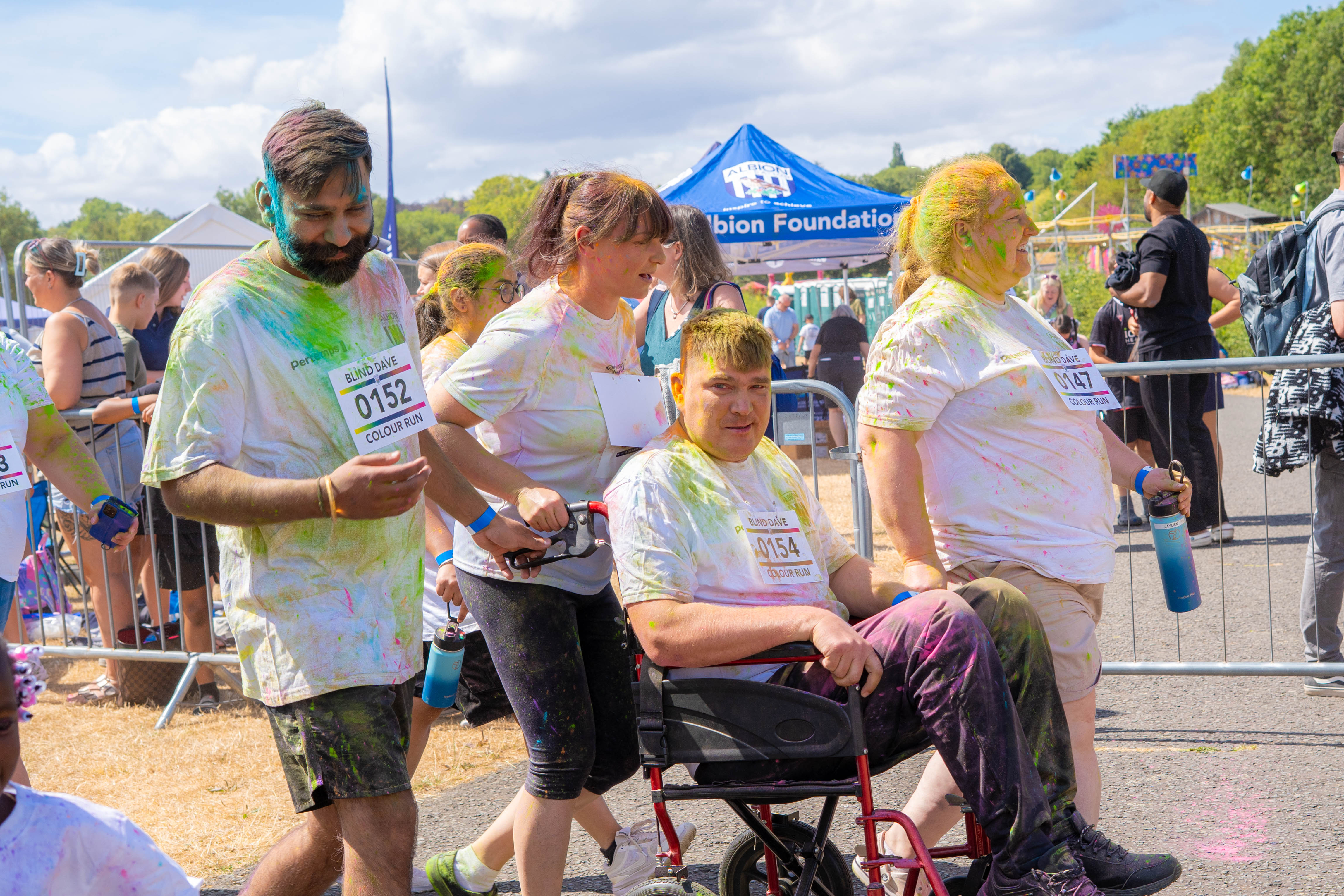 A participant in a wheelchair and other participants walking through the start line.