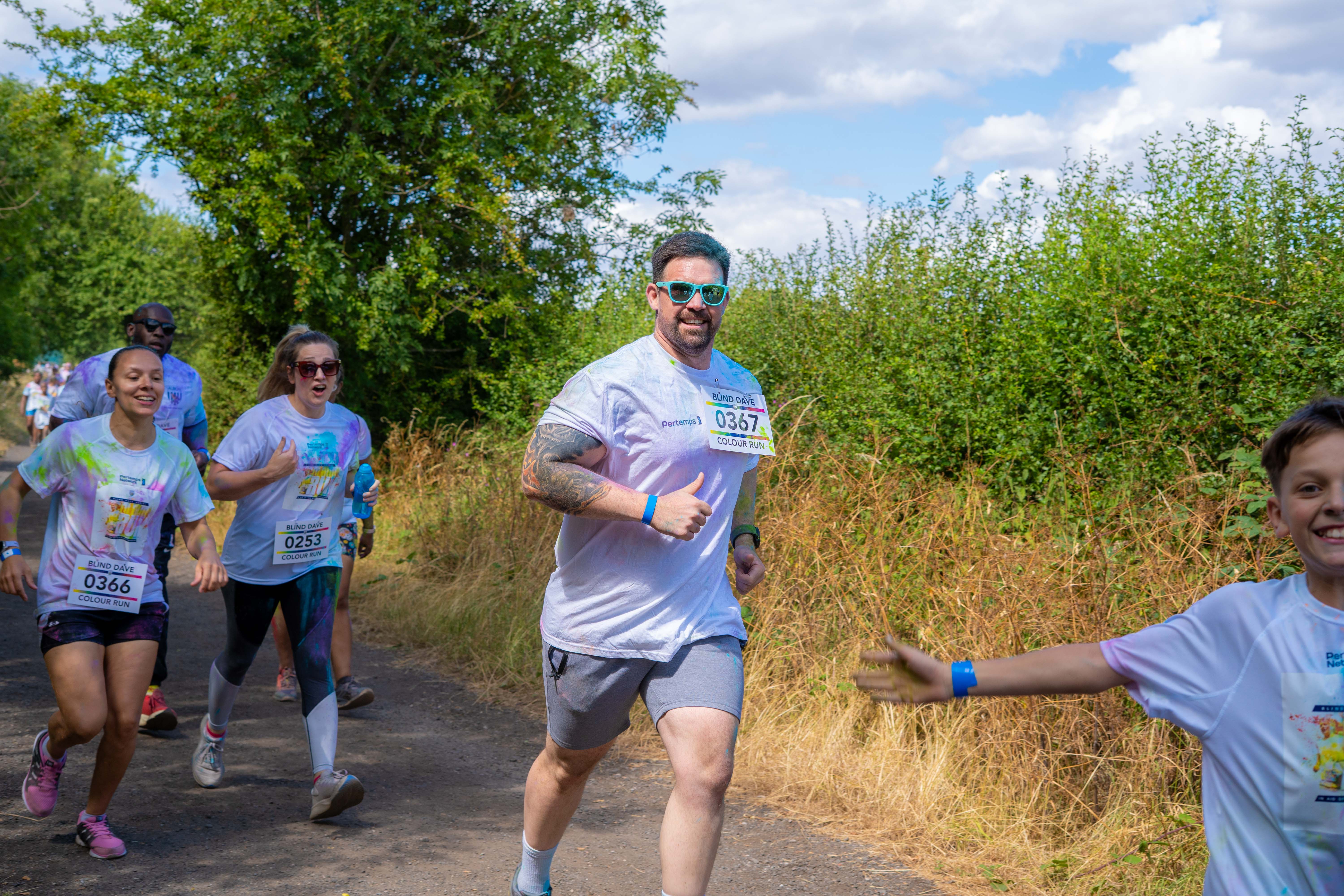 A small group of participants runs along the course surrounded by trees and greenery.