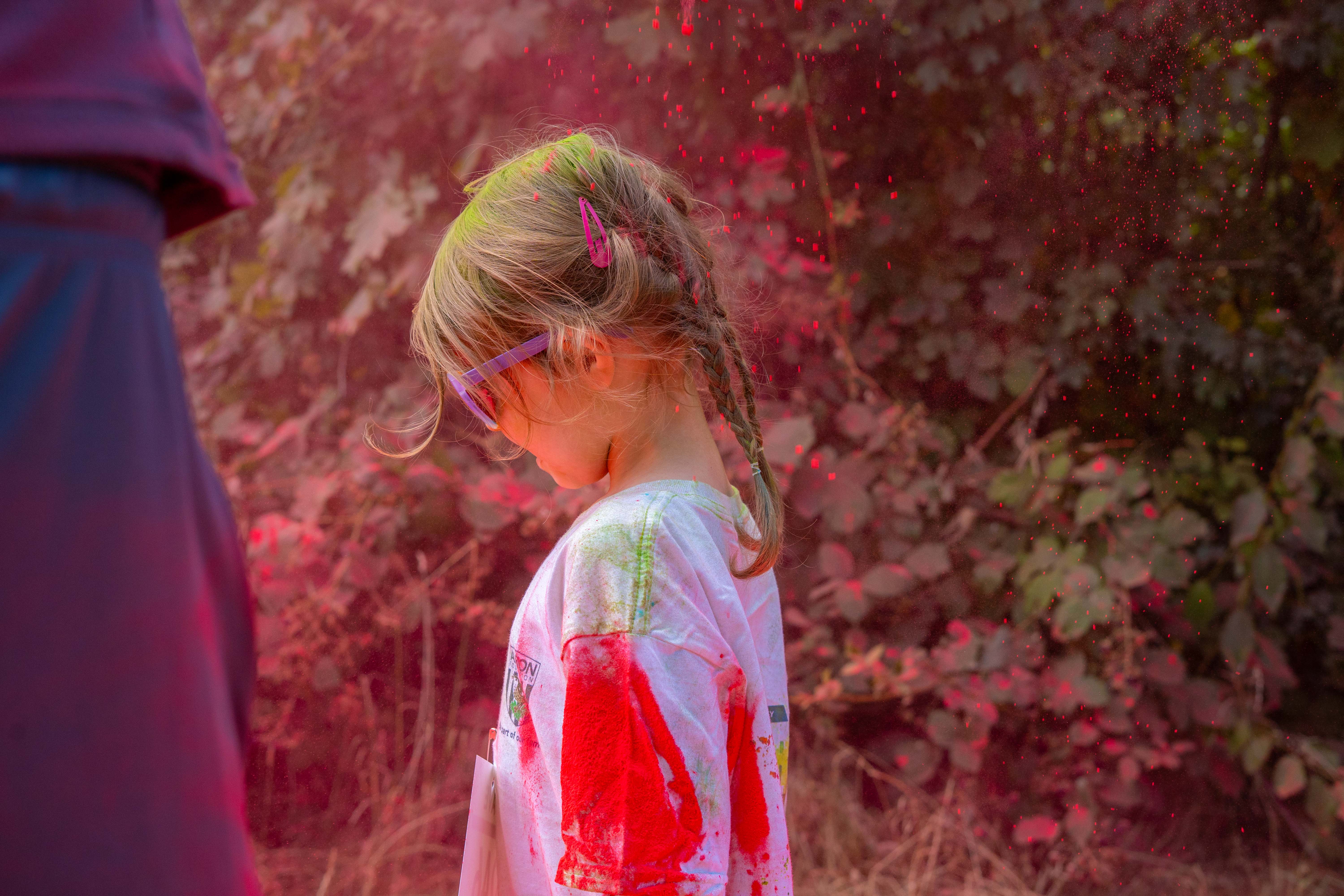 A child participant covered in pink powder walks along the route.