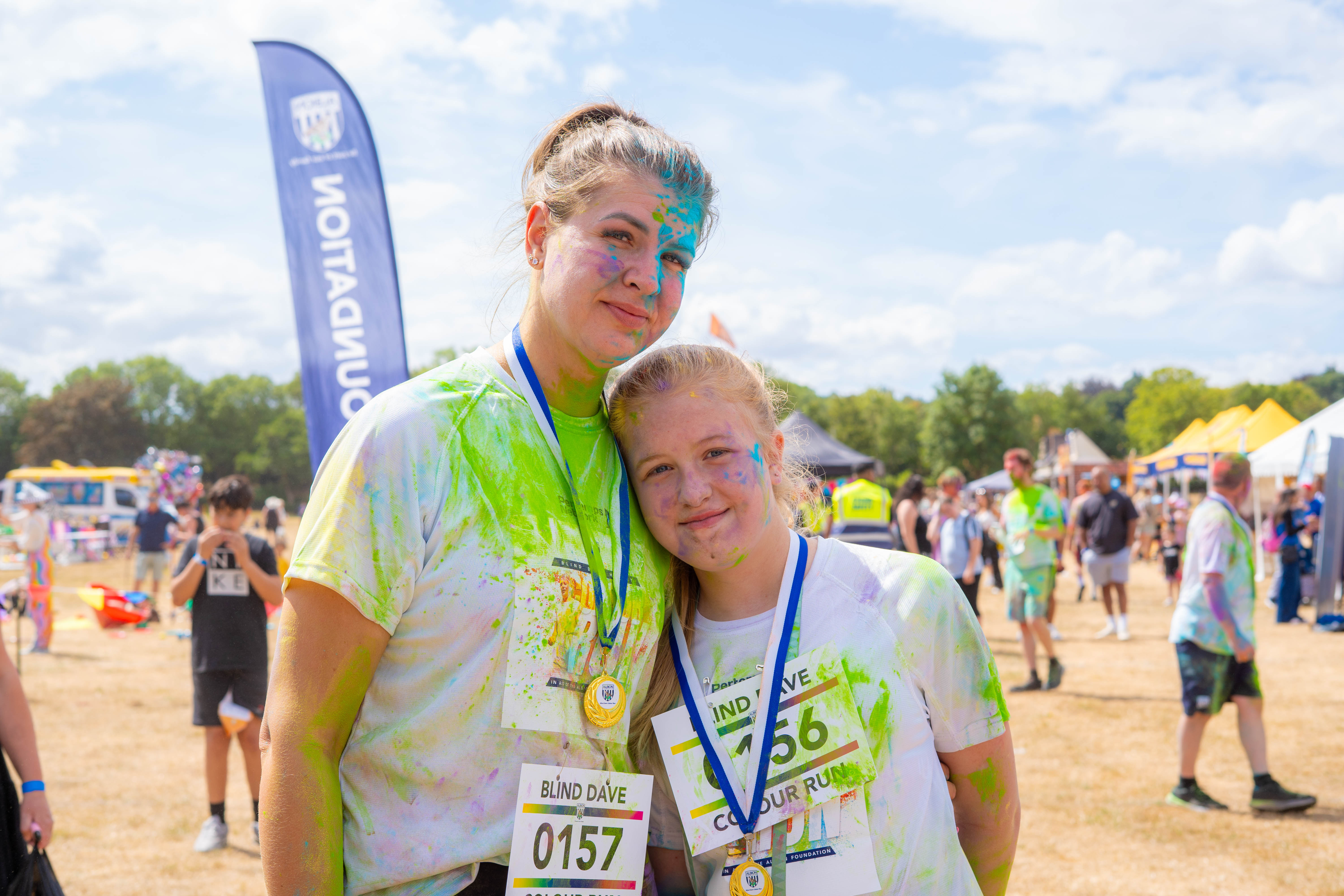 Participant posing after the Blind Dave Colour Run, wearing a finisher medal.