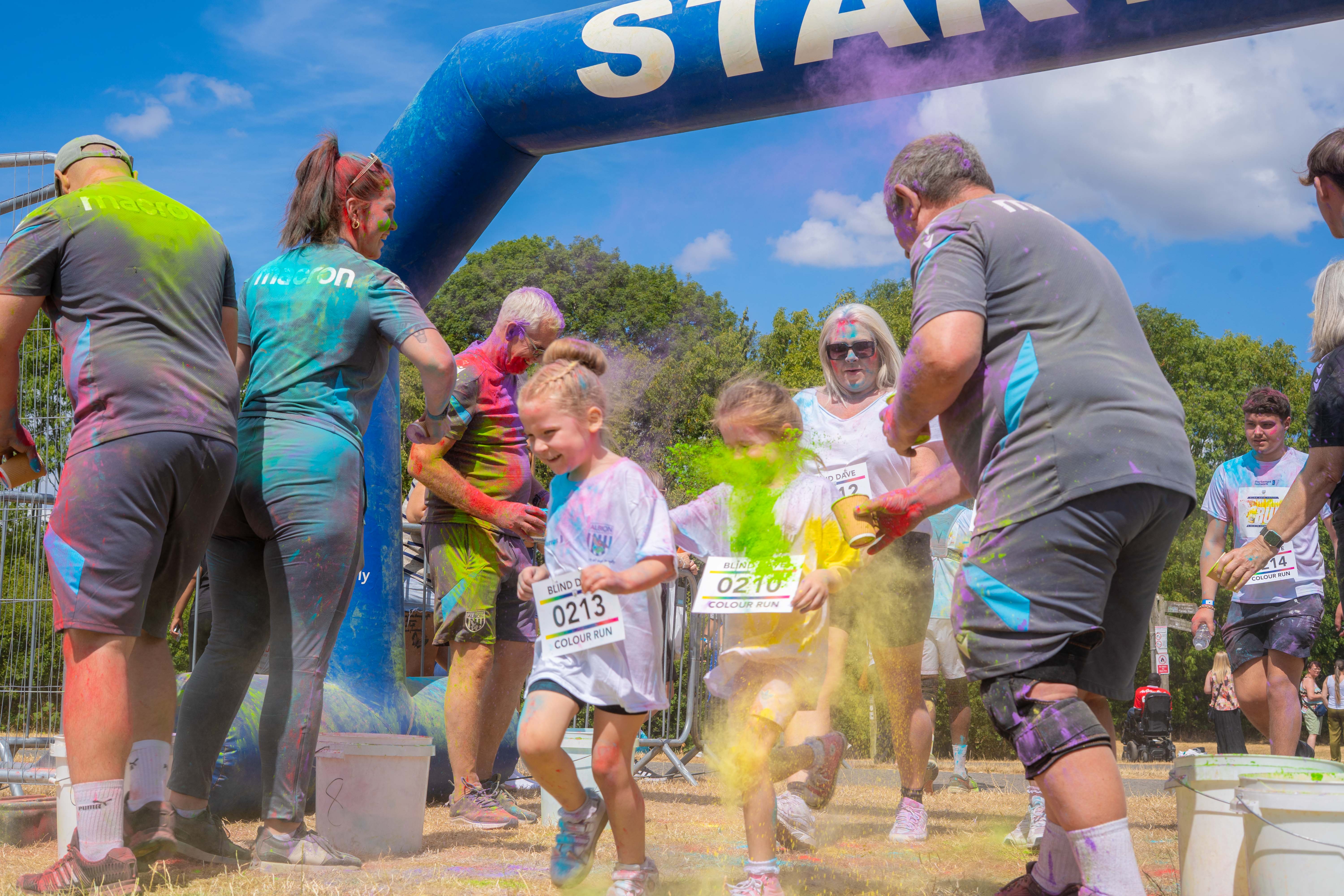 Participants and staff interacting and throwing paint near the event finish area.
