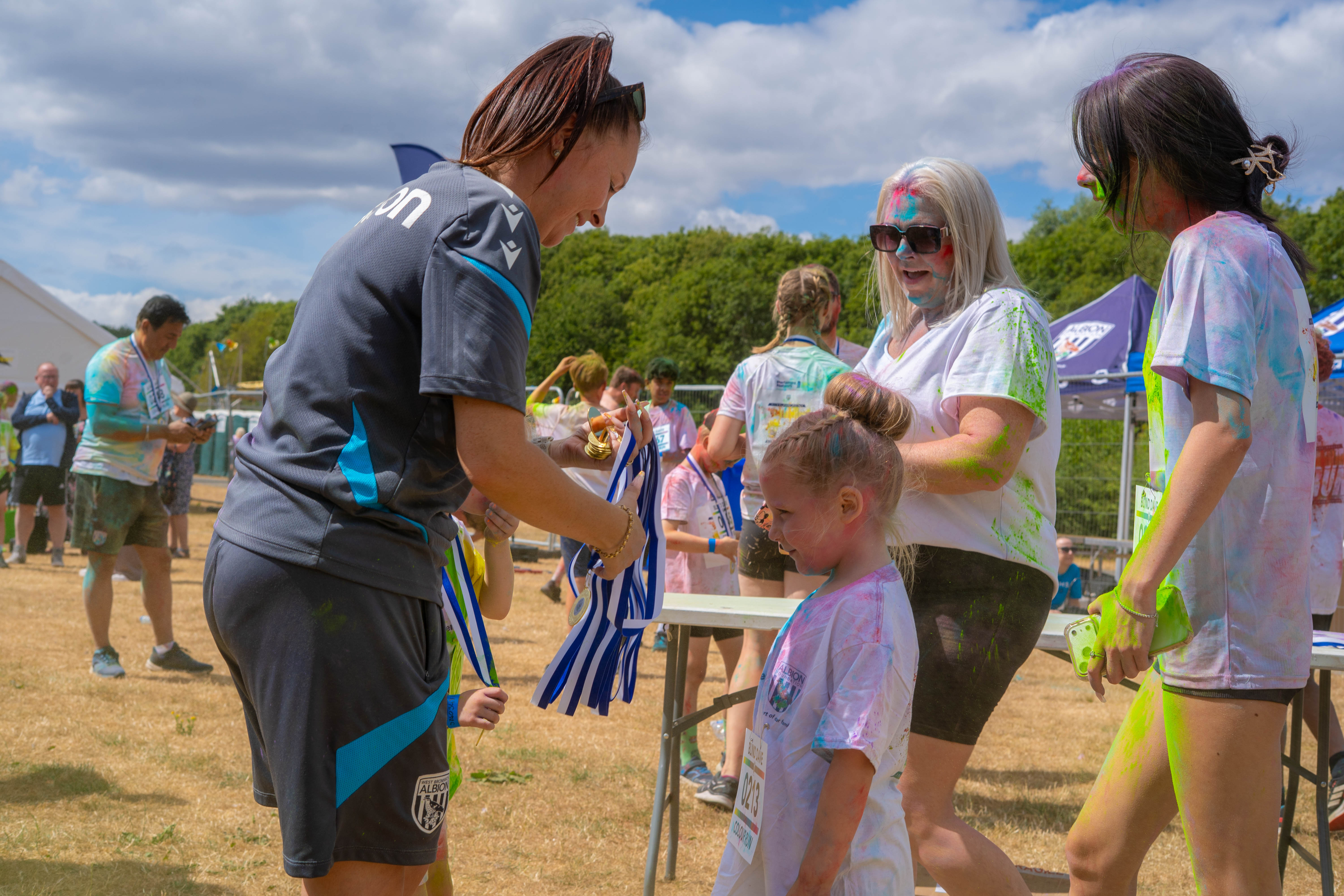 Staff member assisting young participants with medal at the finish area.