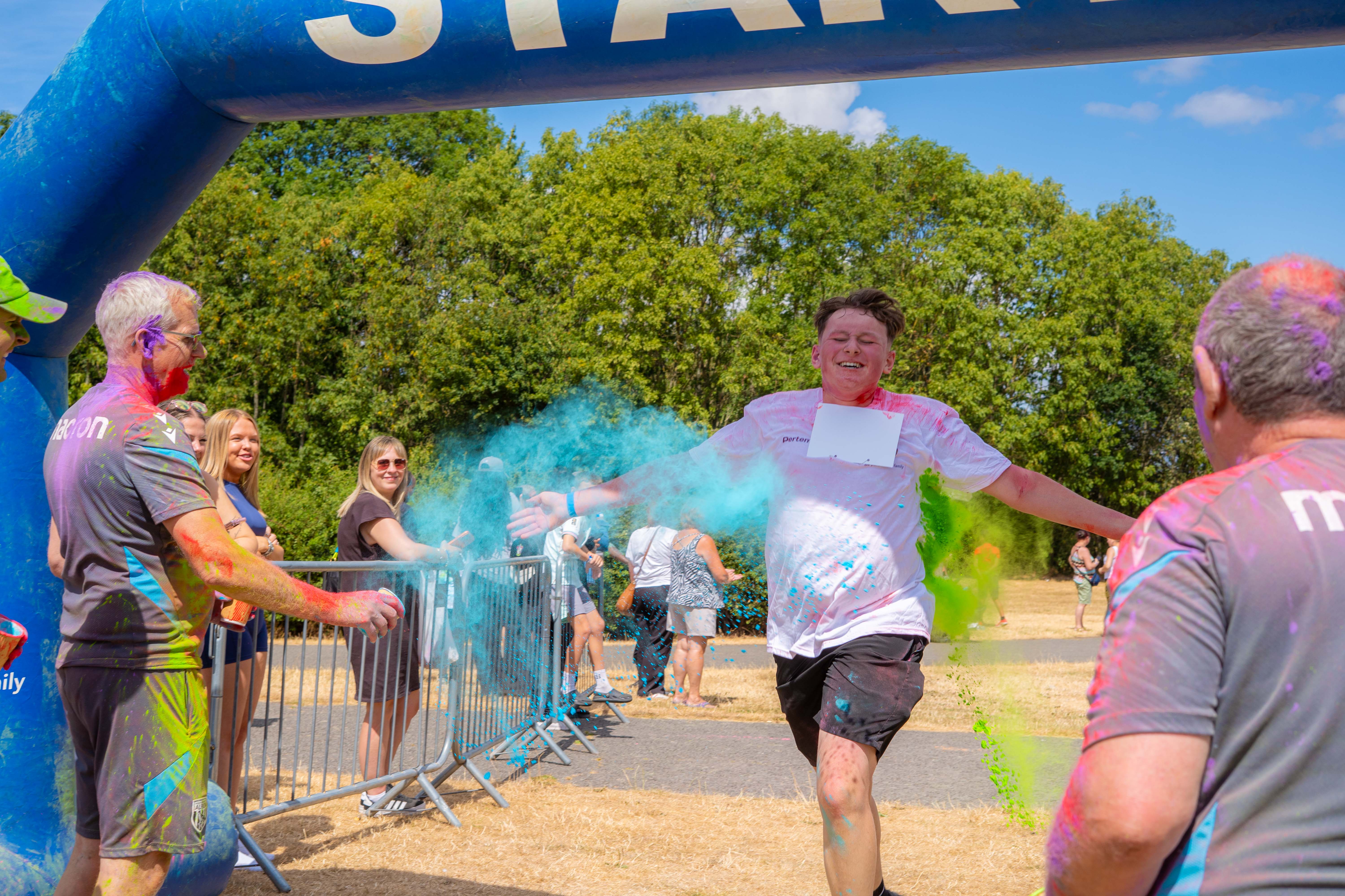 Participant running through coloured powder near the FINISH arch.