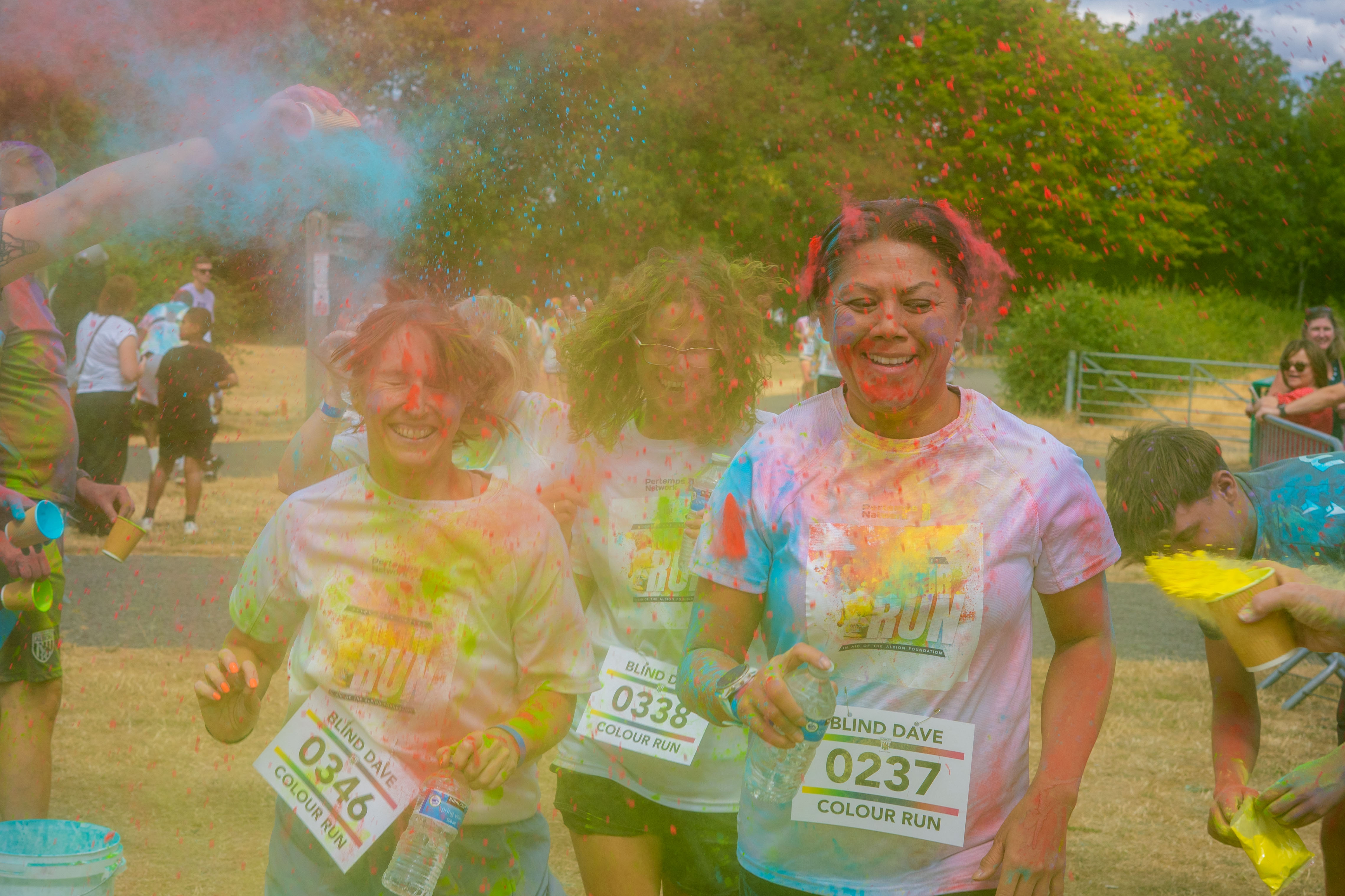 Participants running through the finish area covered in paint.