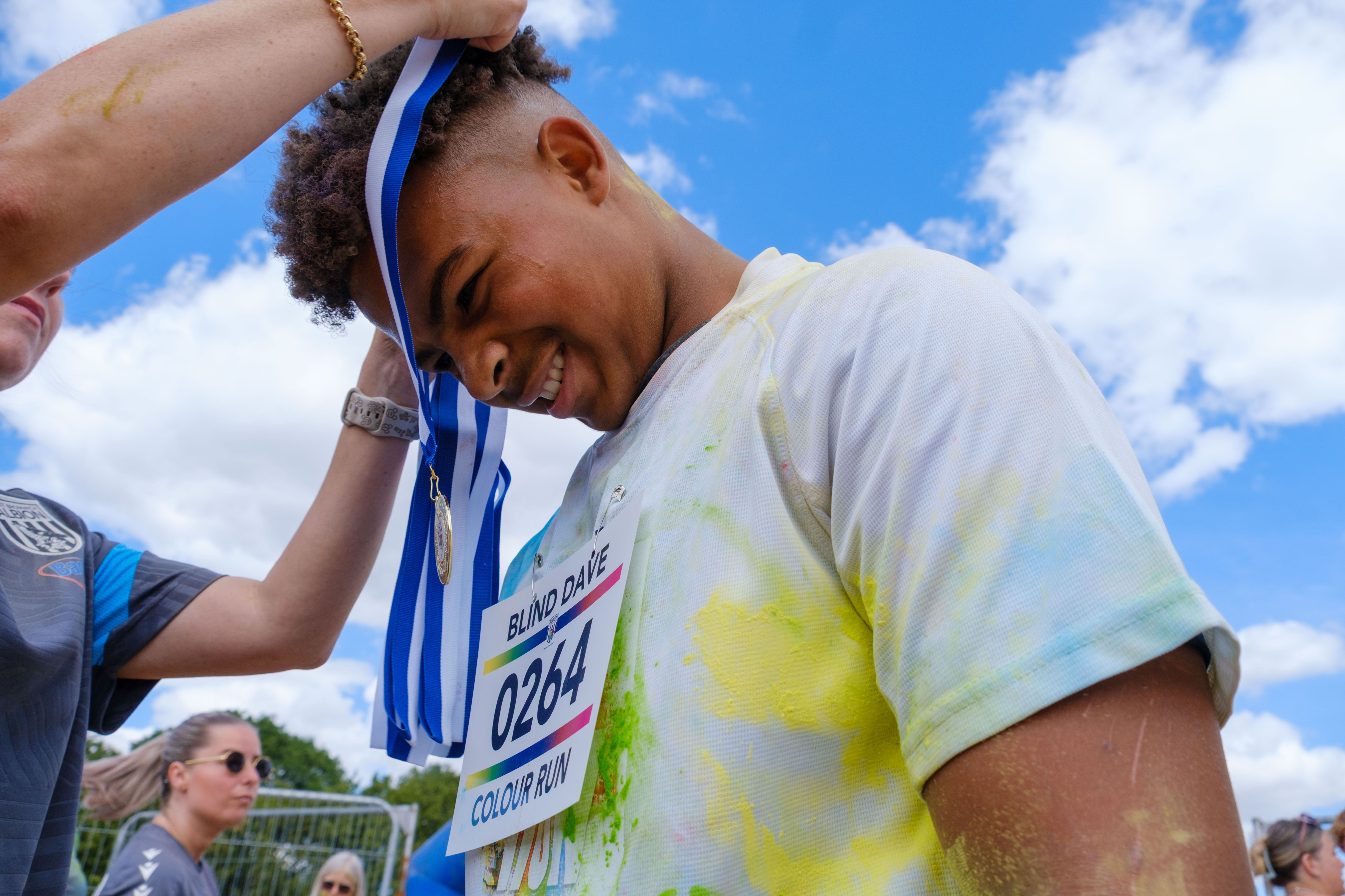 Staff member placing a medal around a participant's neck.
