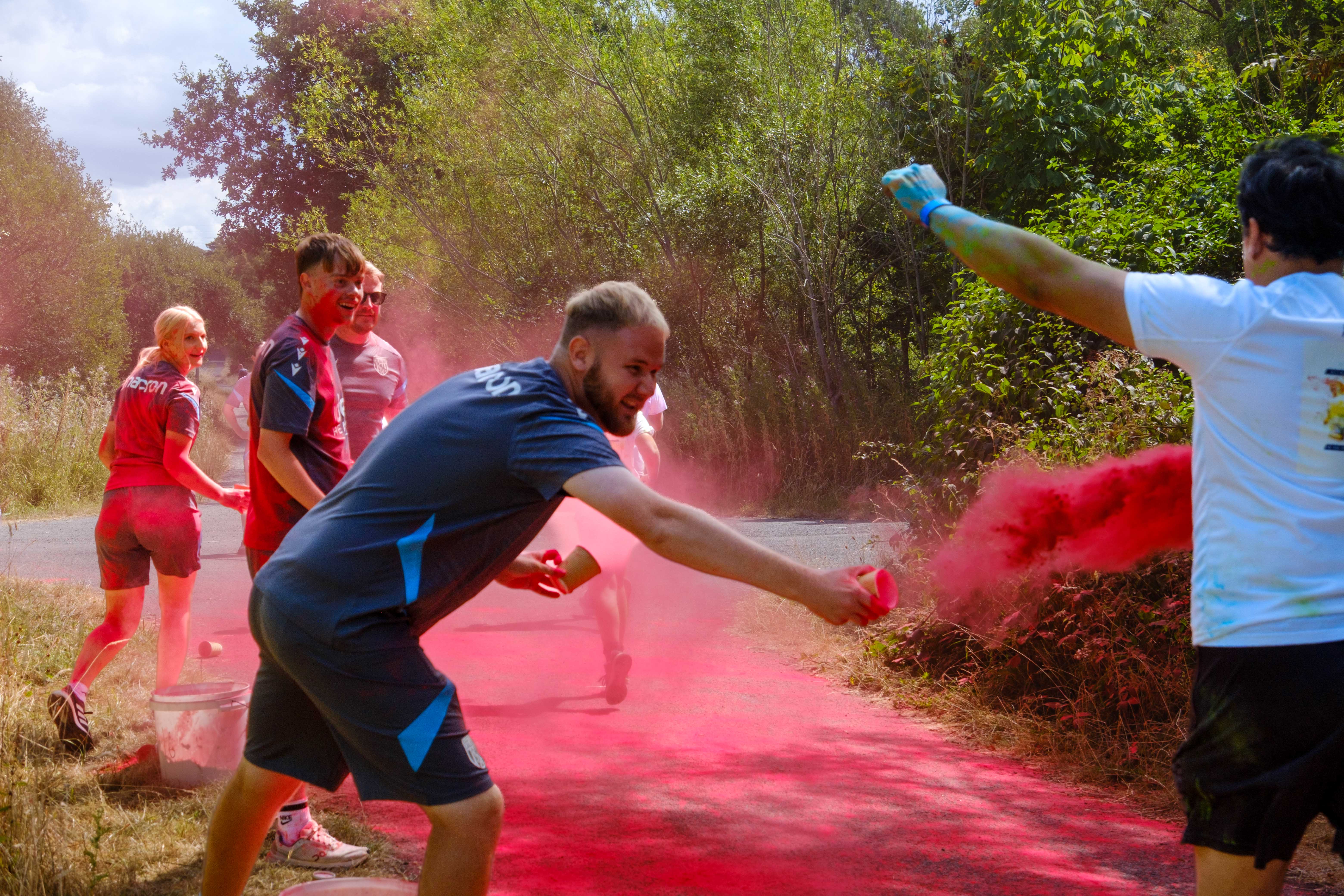A participant runs through a cloud of pink color powder.