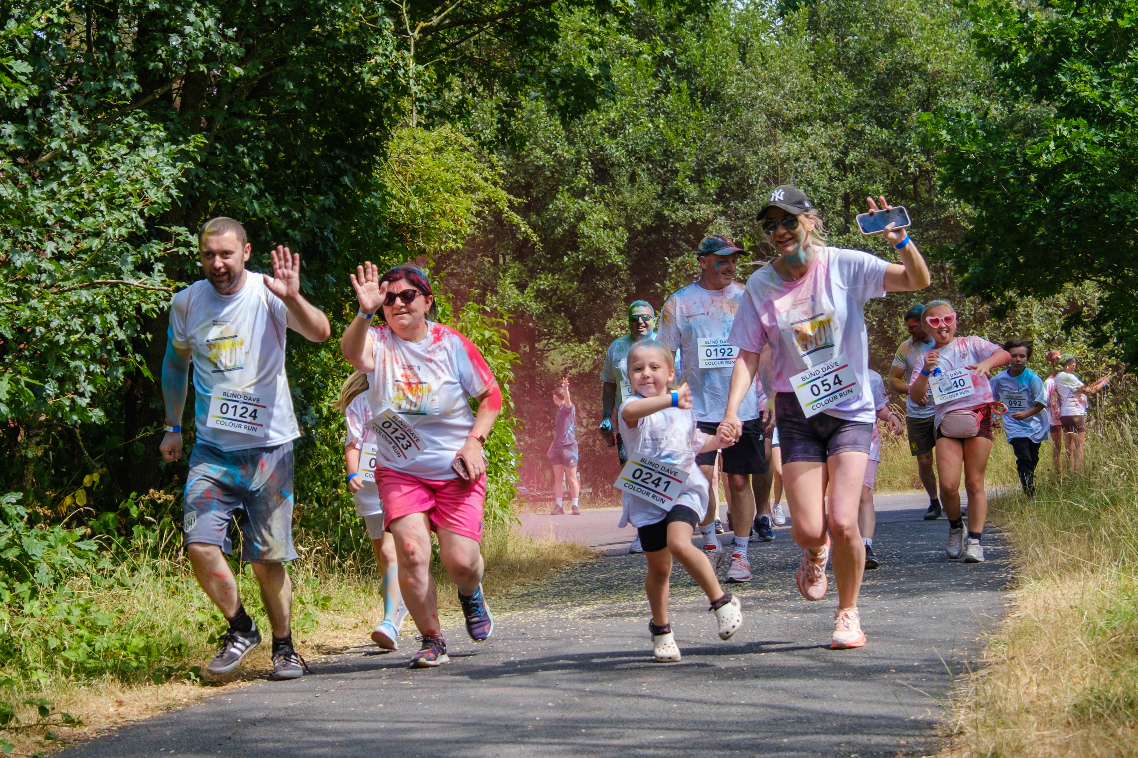 A group of participants walks and runs along a shaded path.