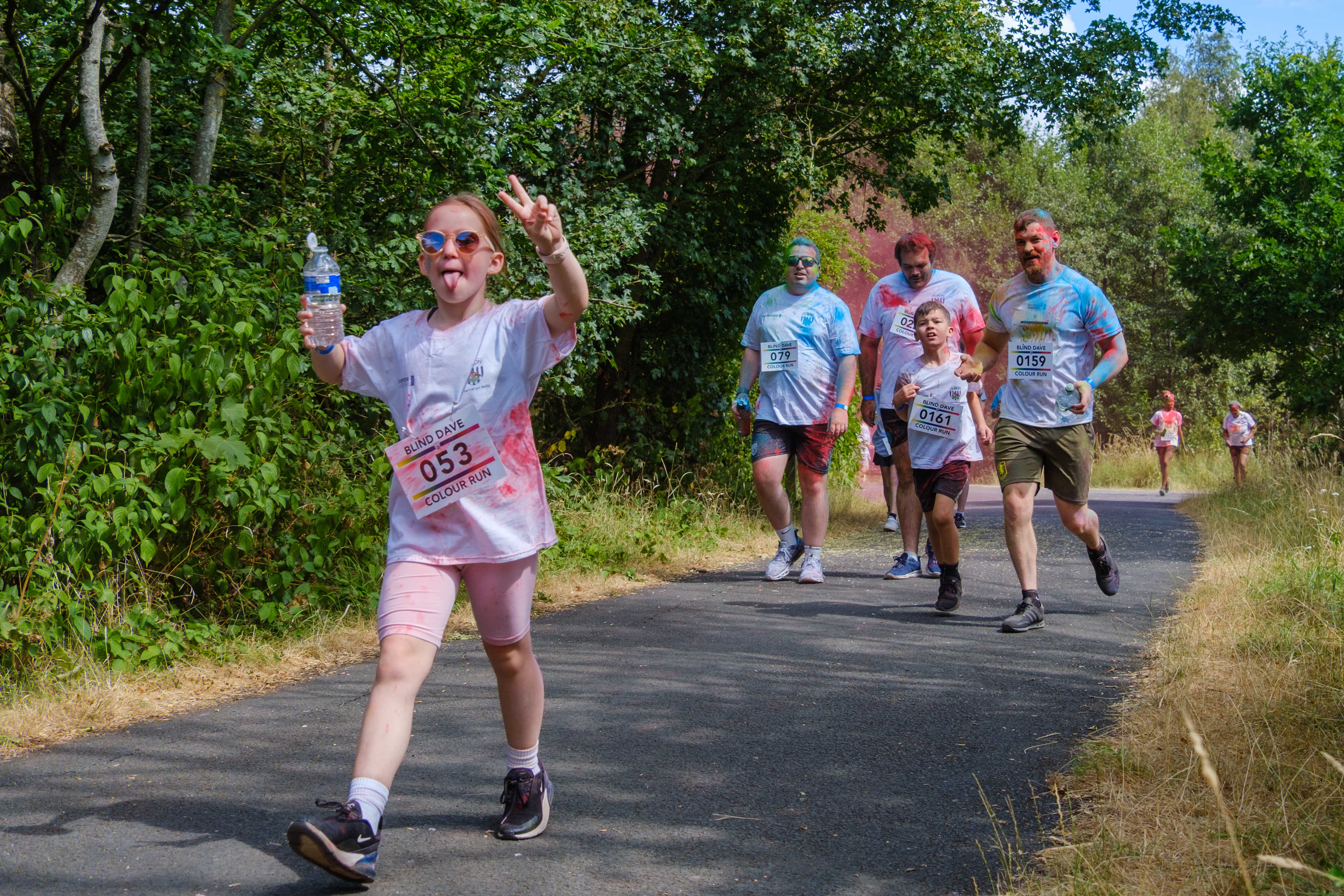 A participant waves while walking ahead of other participants on the course.