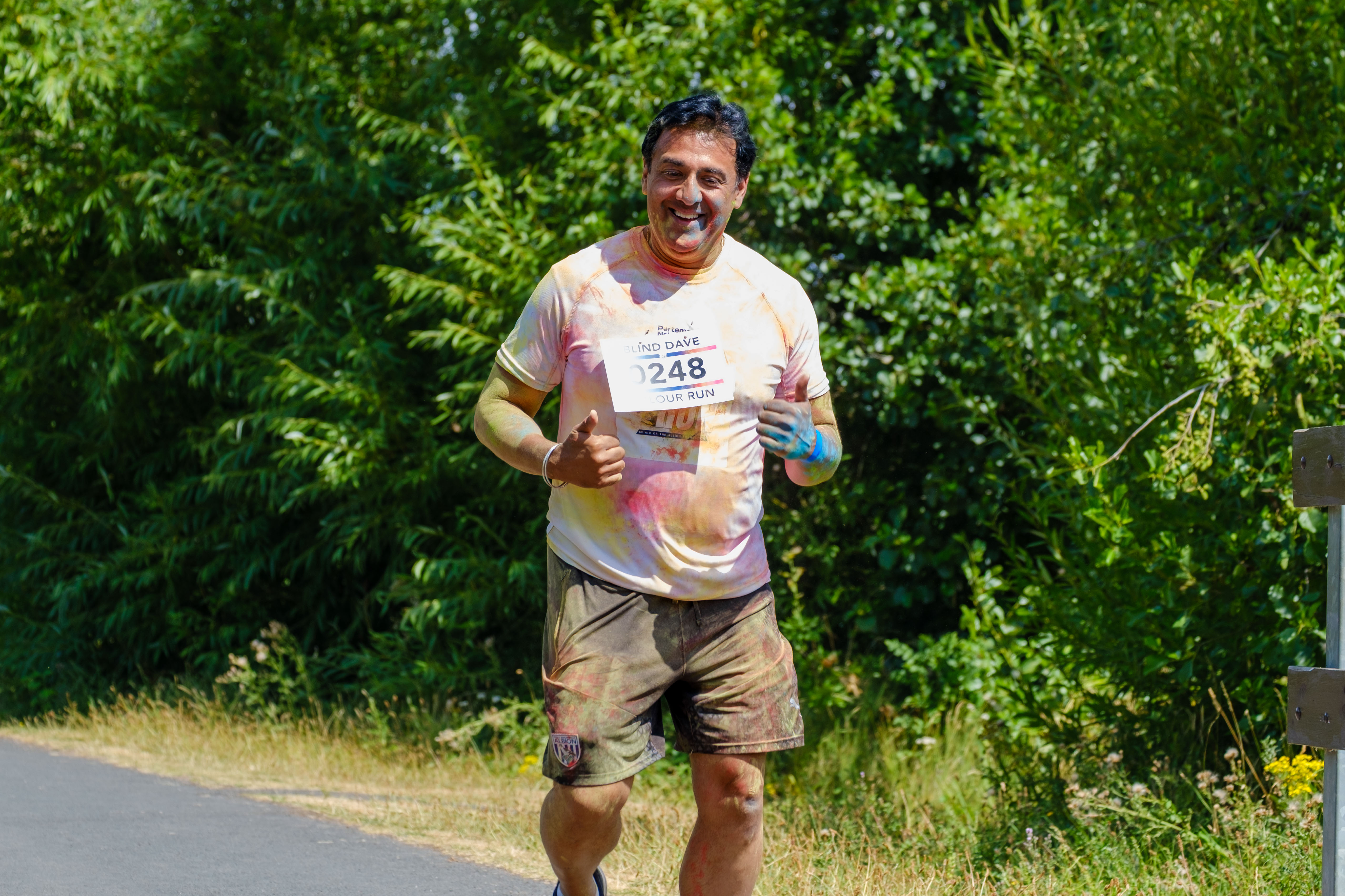 A participant runs alone along a tree-lined section of the route.