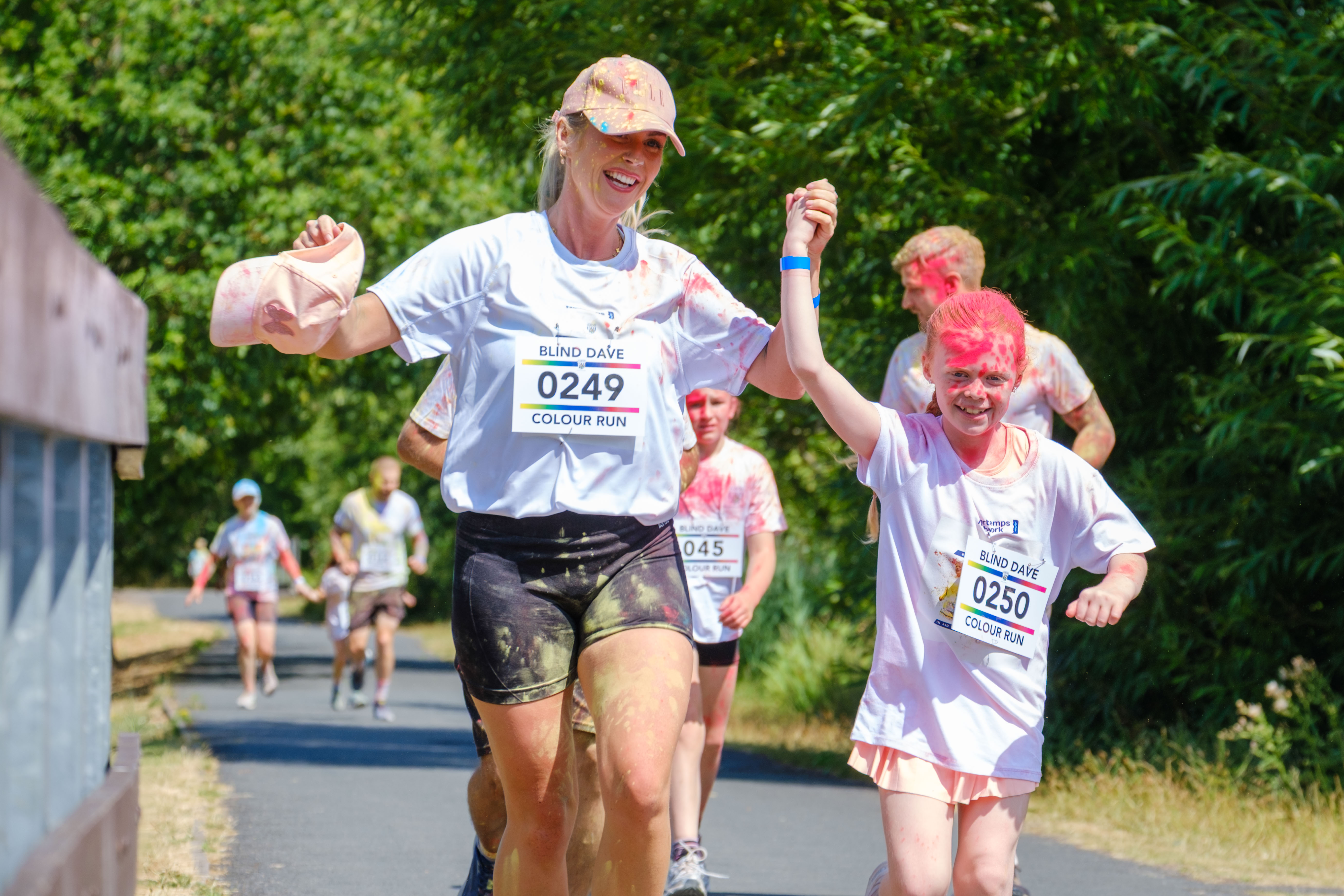 Two participants covered in color powder run side by side.