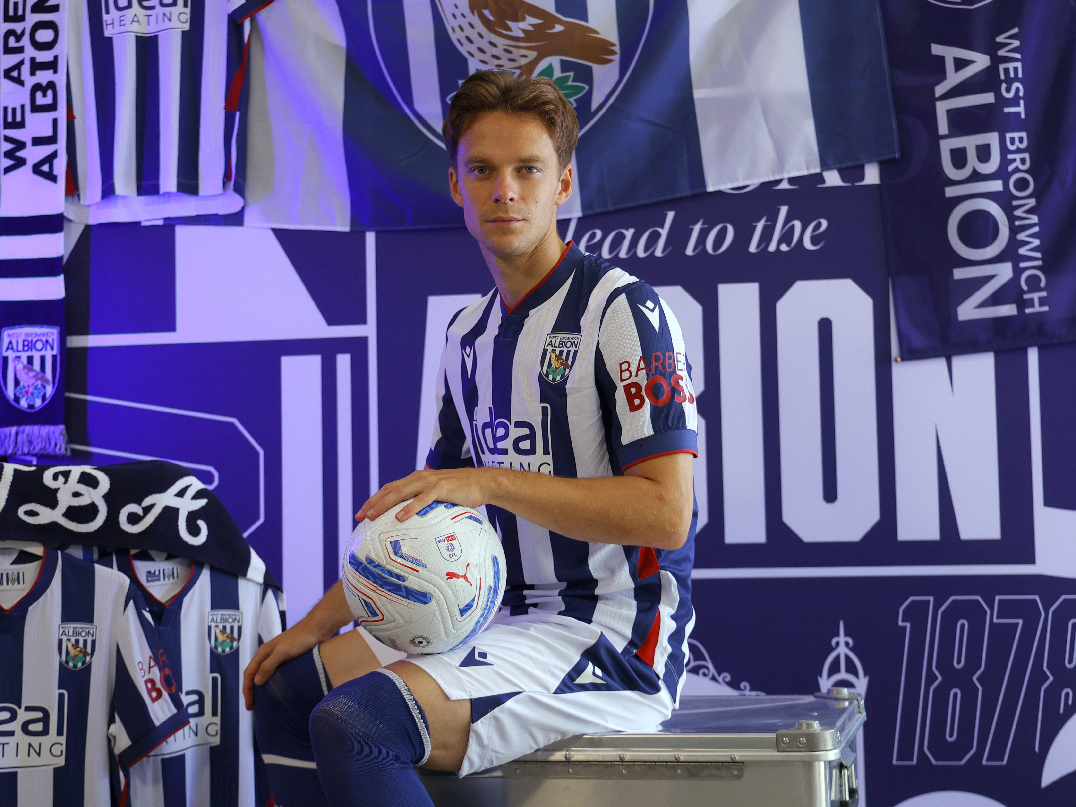 Felix Horn Myhre in the home kit sat looking at the camera in front of WBA branding 