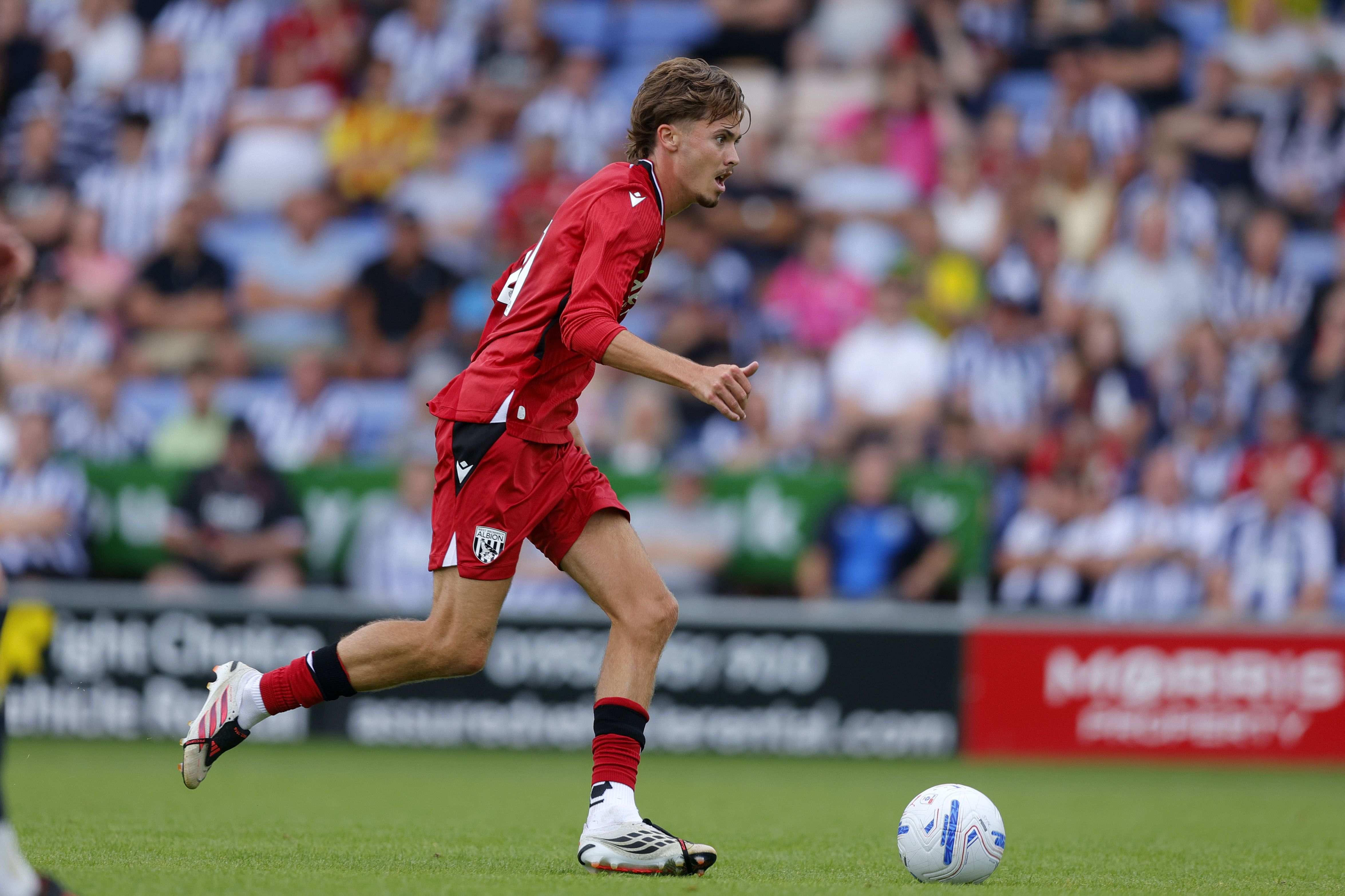 Isaac Price on the ball for WBA during a pre-season game in the red away kit 