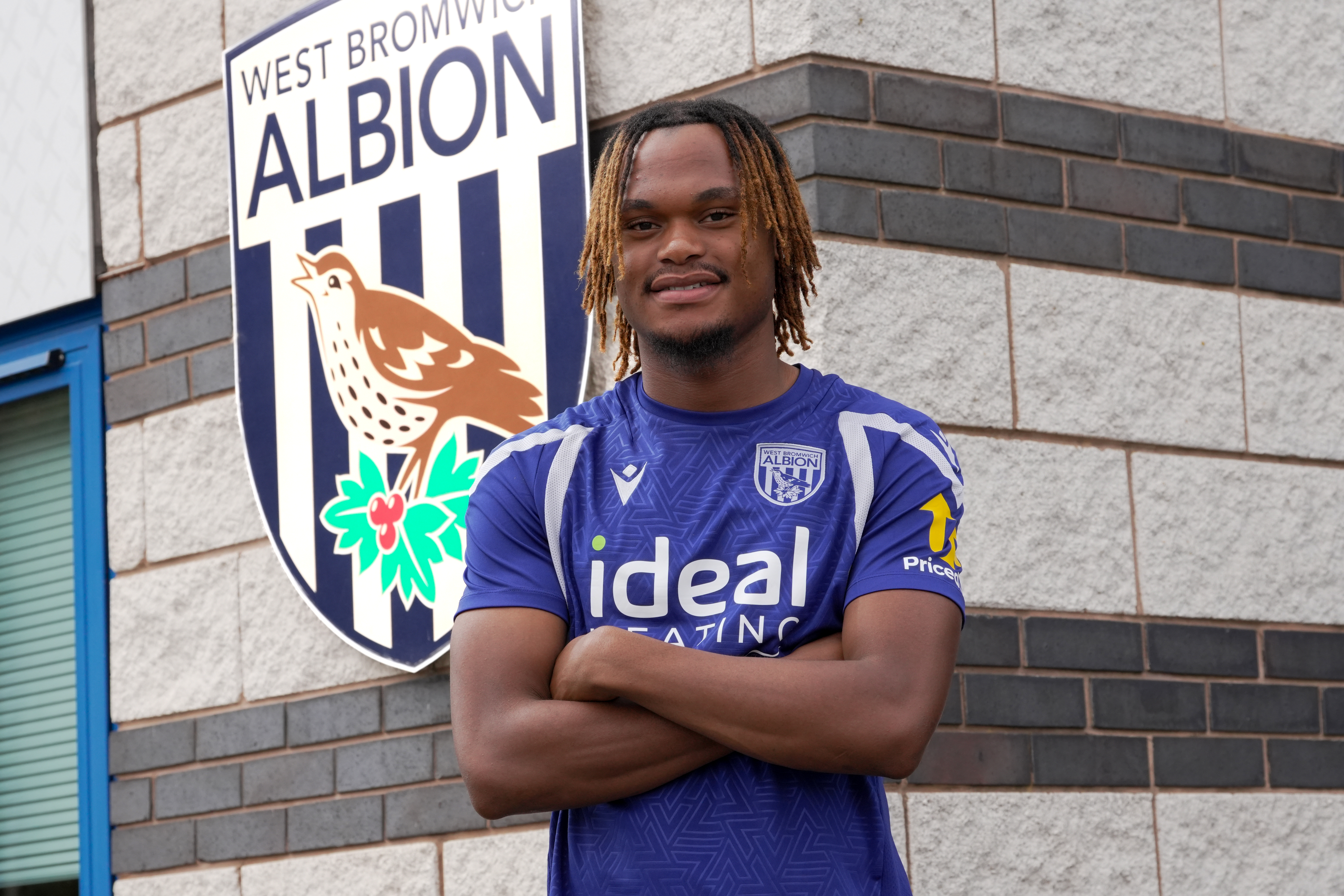 Nathan Dlamini poses next to a club crest on the wall