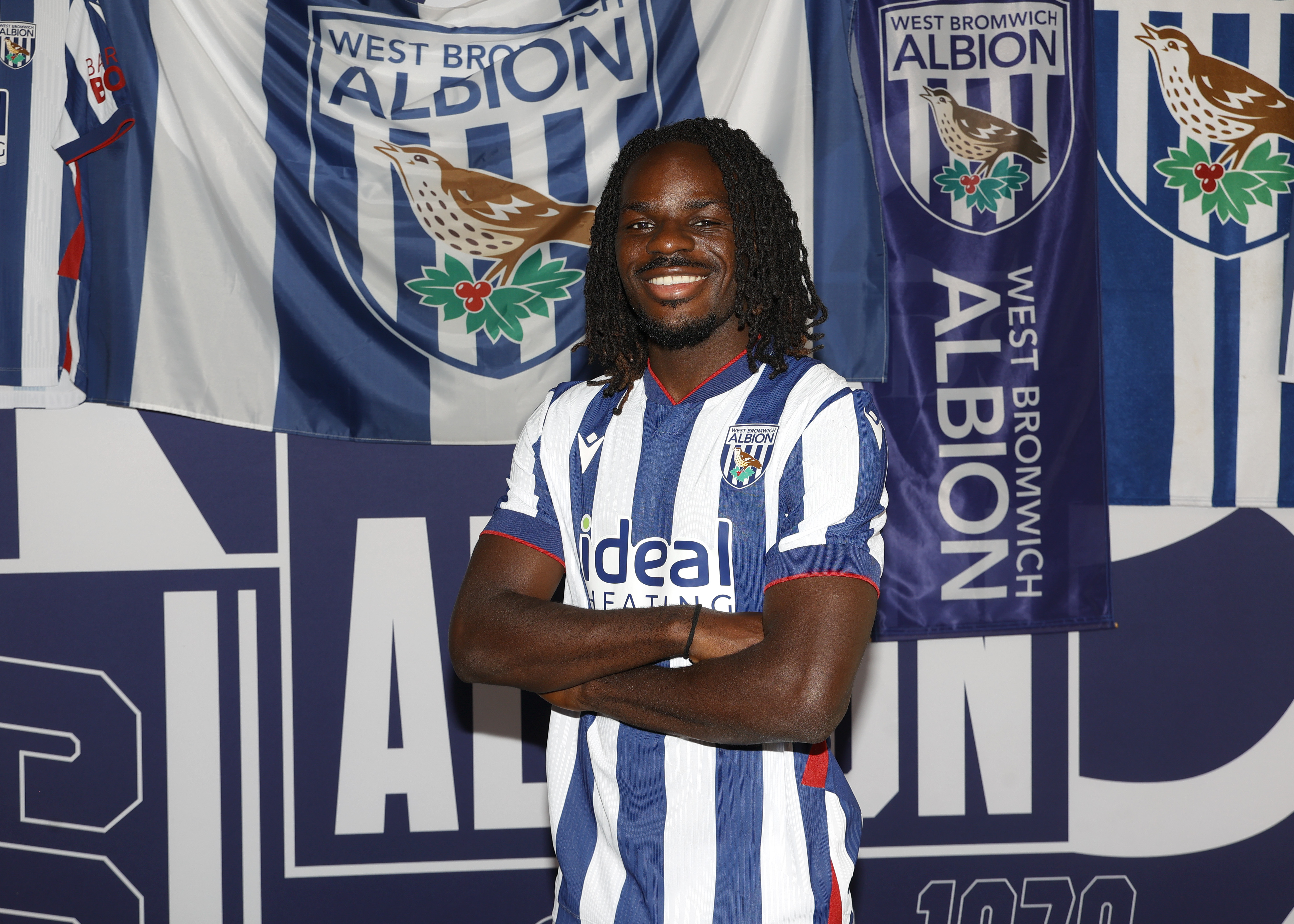 Brayann Pereira smiling at the camera while stood in a home shirt in front of WBA branding 