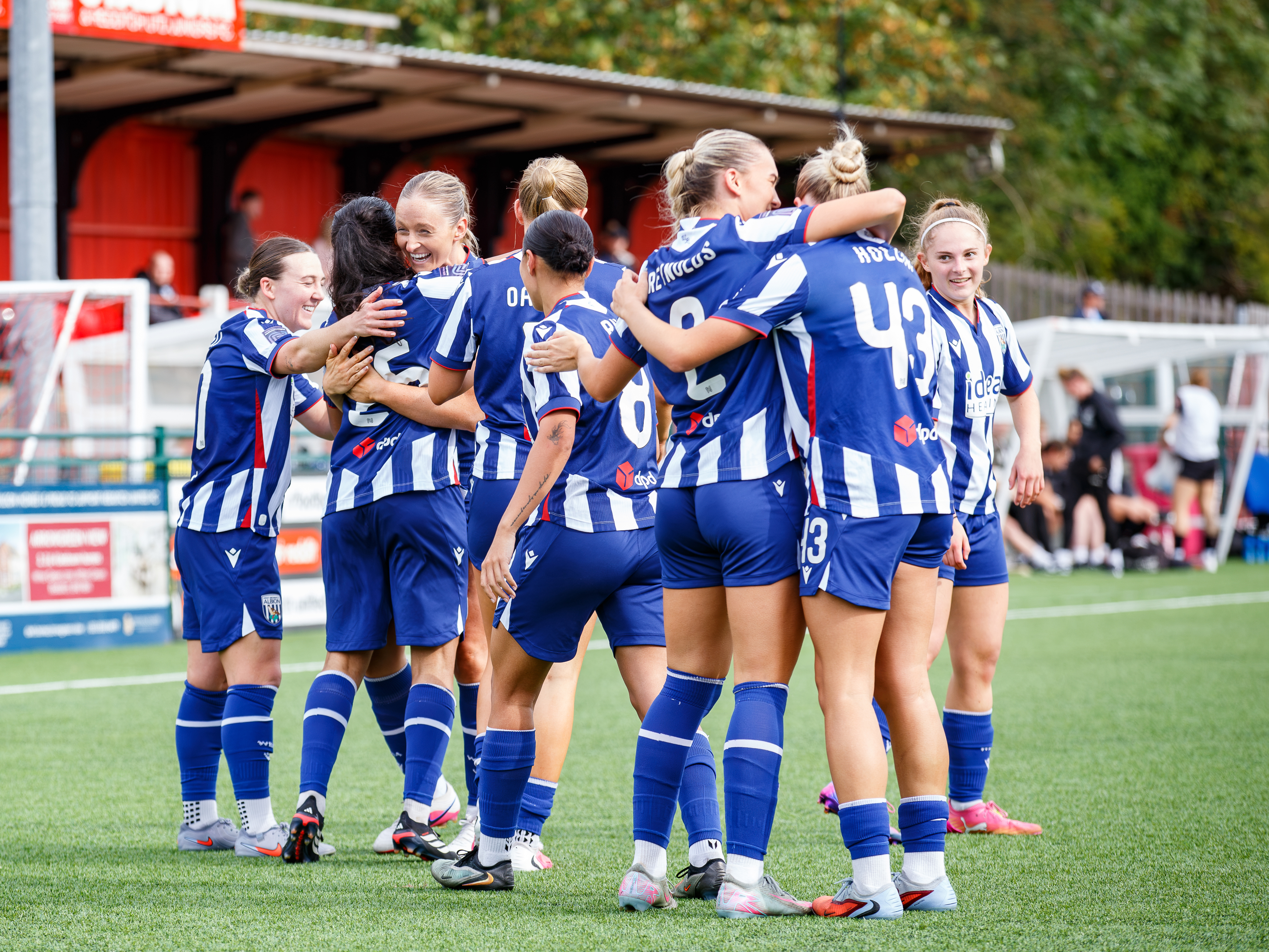 Albion Women players celebrate a goal scored against Peterborough in the home kit 