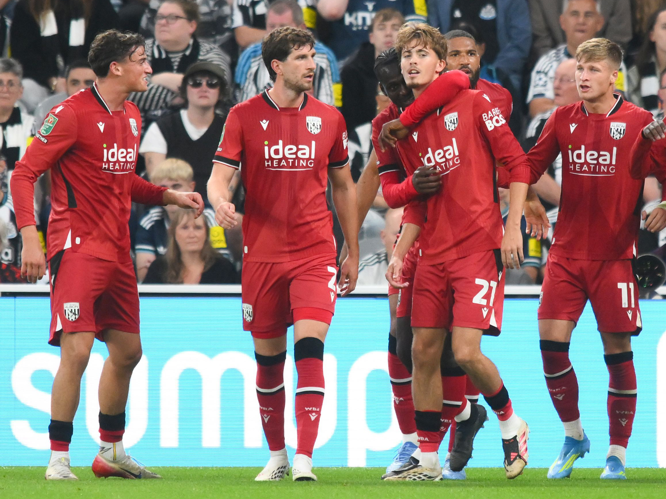 Isaac Price celebrates his Newcastle goal with team-mates in the red away kit 