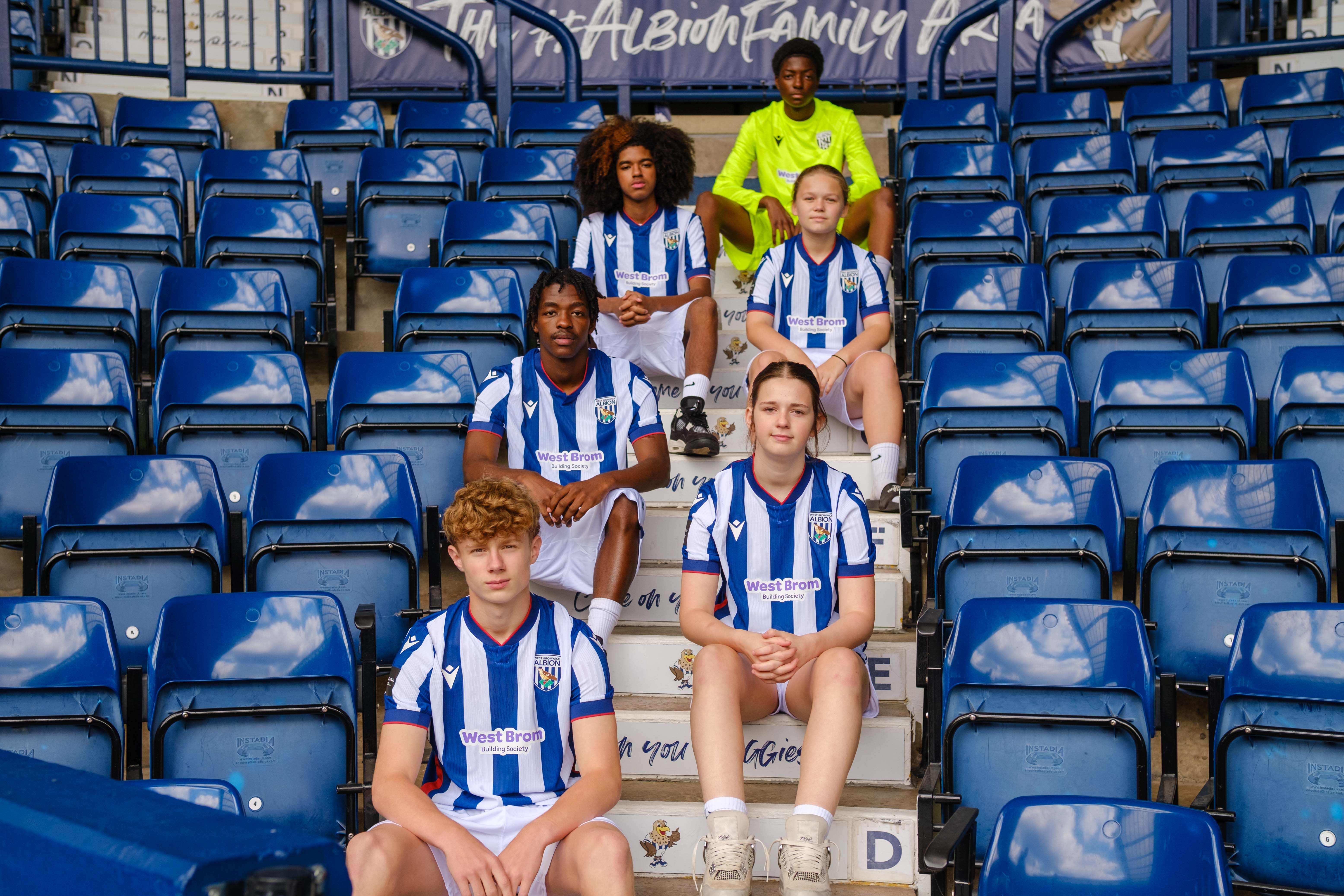 Six Post-16 players sitting on the steps on the East Stand.