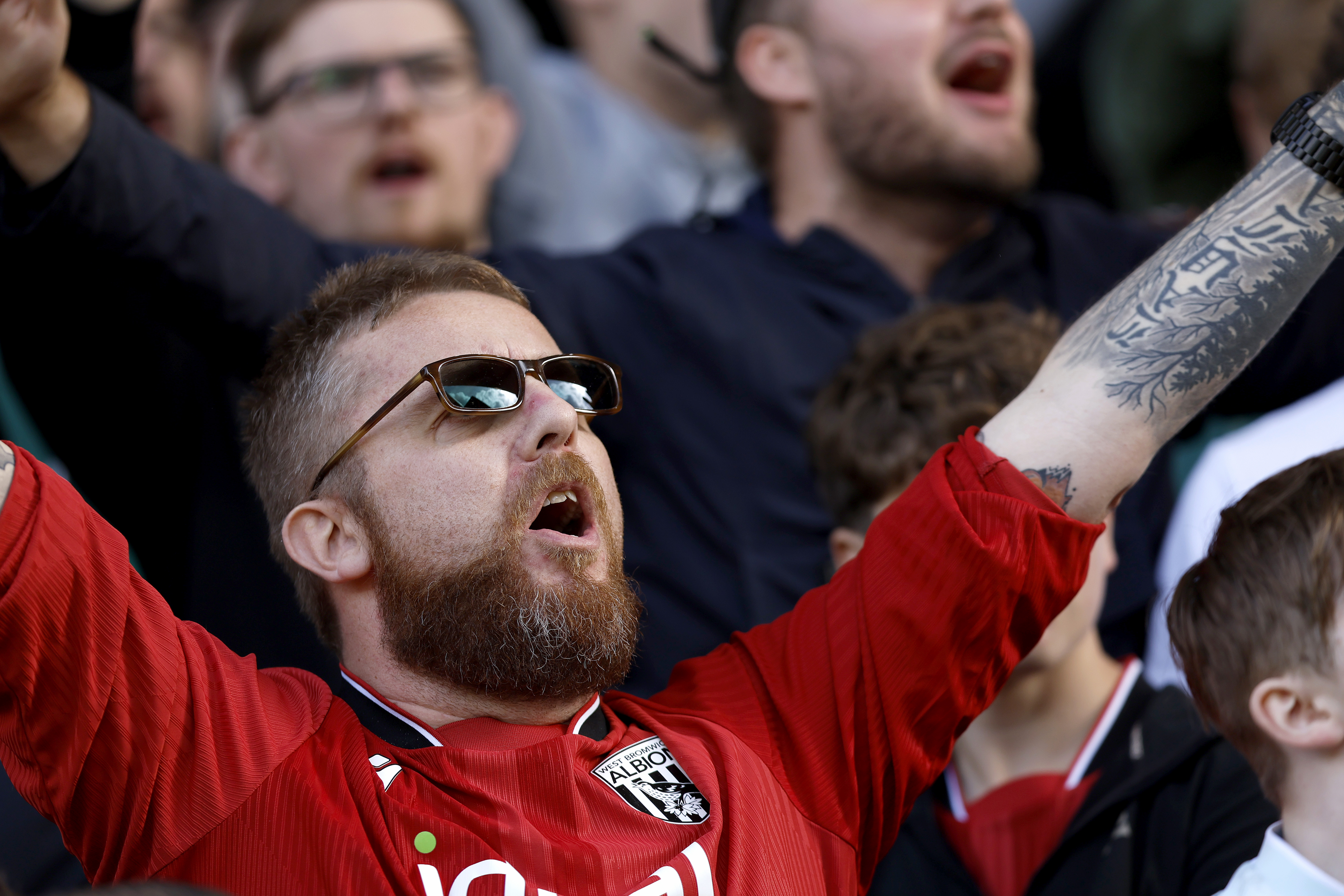 A WBA fan cheering while wearing a red away shirt 