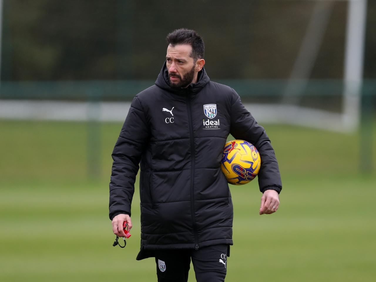 Carlos Corberán holding a football while watching training 