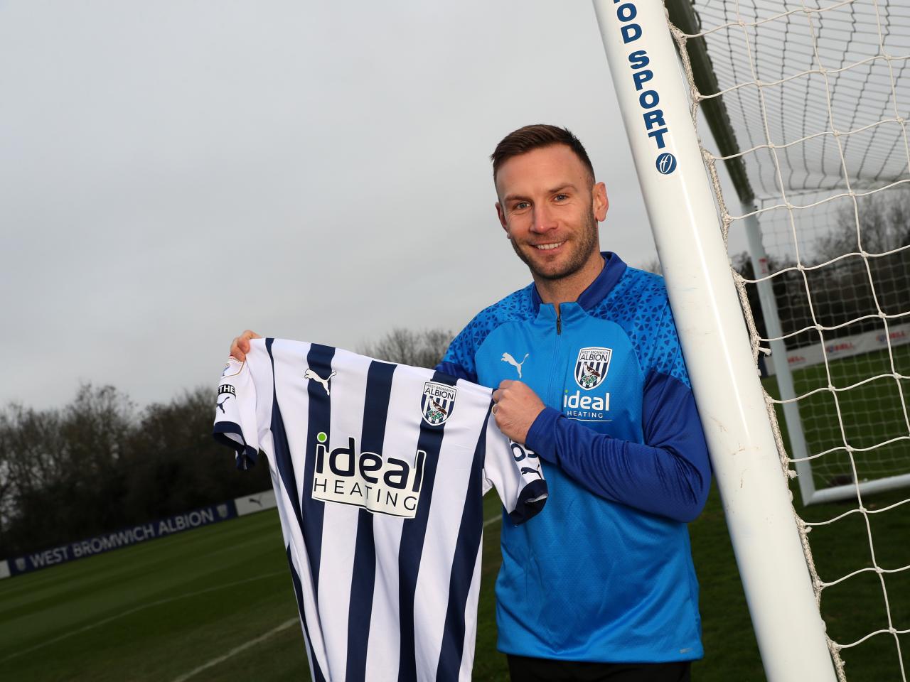 Andi Weimann smiling while holding up an Albion shirt