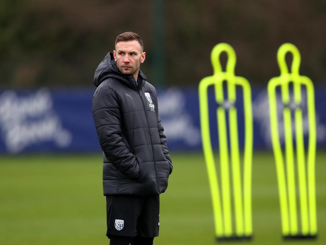 Andi Weimann watching training in a black coat