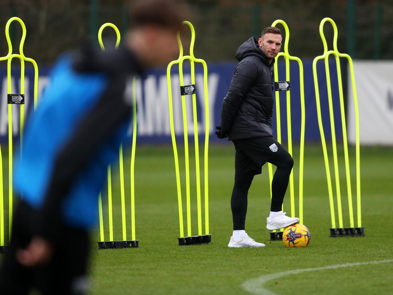 Andi Weimann watching training in a black coat while stood on a ball