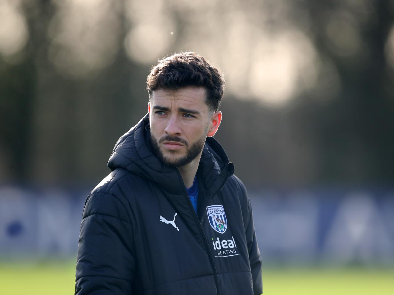 Mikey Johnston watching a training session wearing a big Albion coat