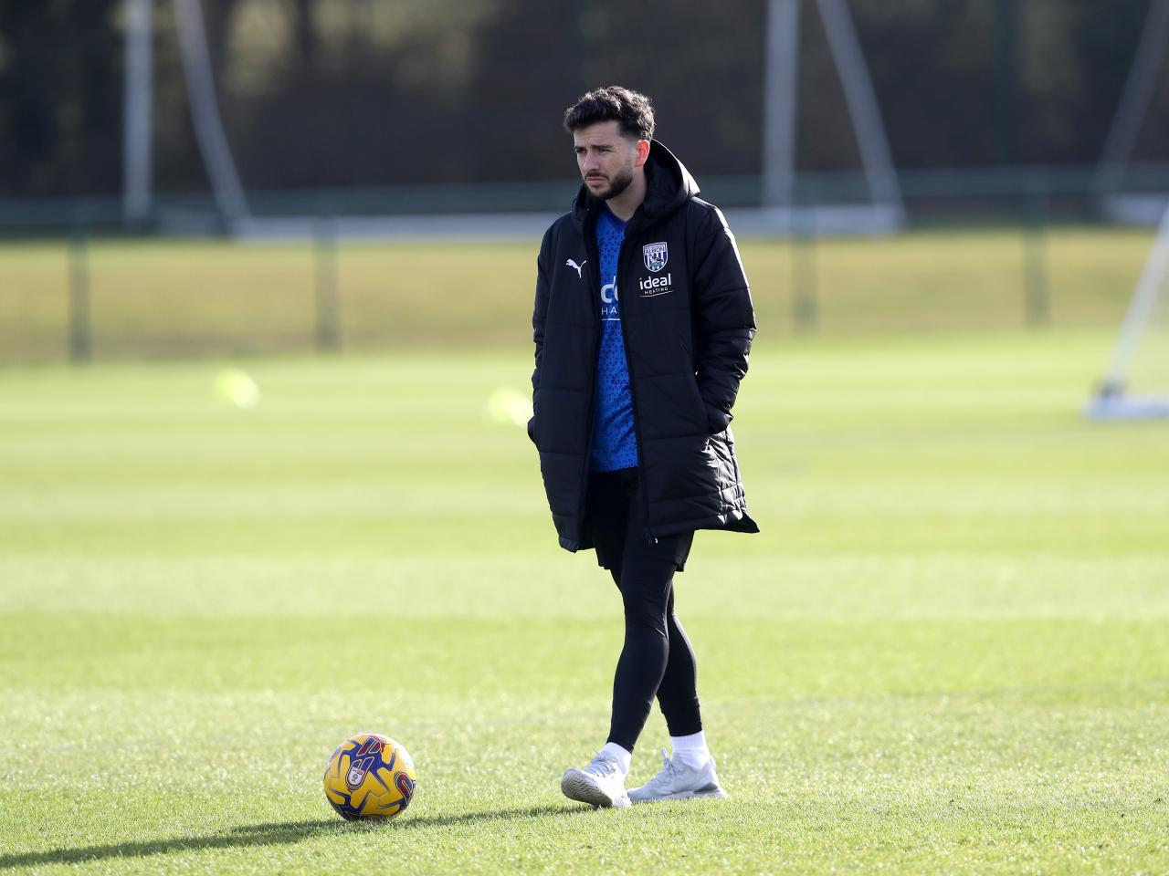 Mikey Johnston watching a training session wearing a big Albion coat