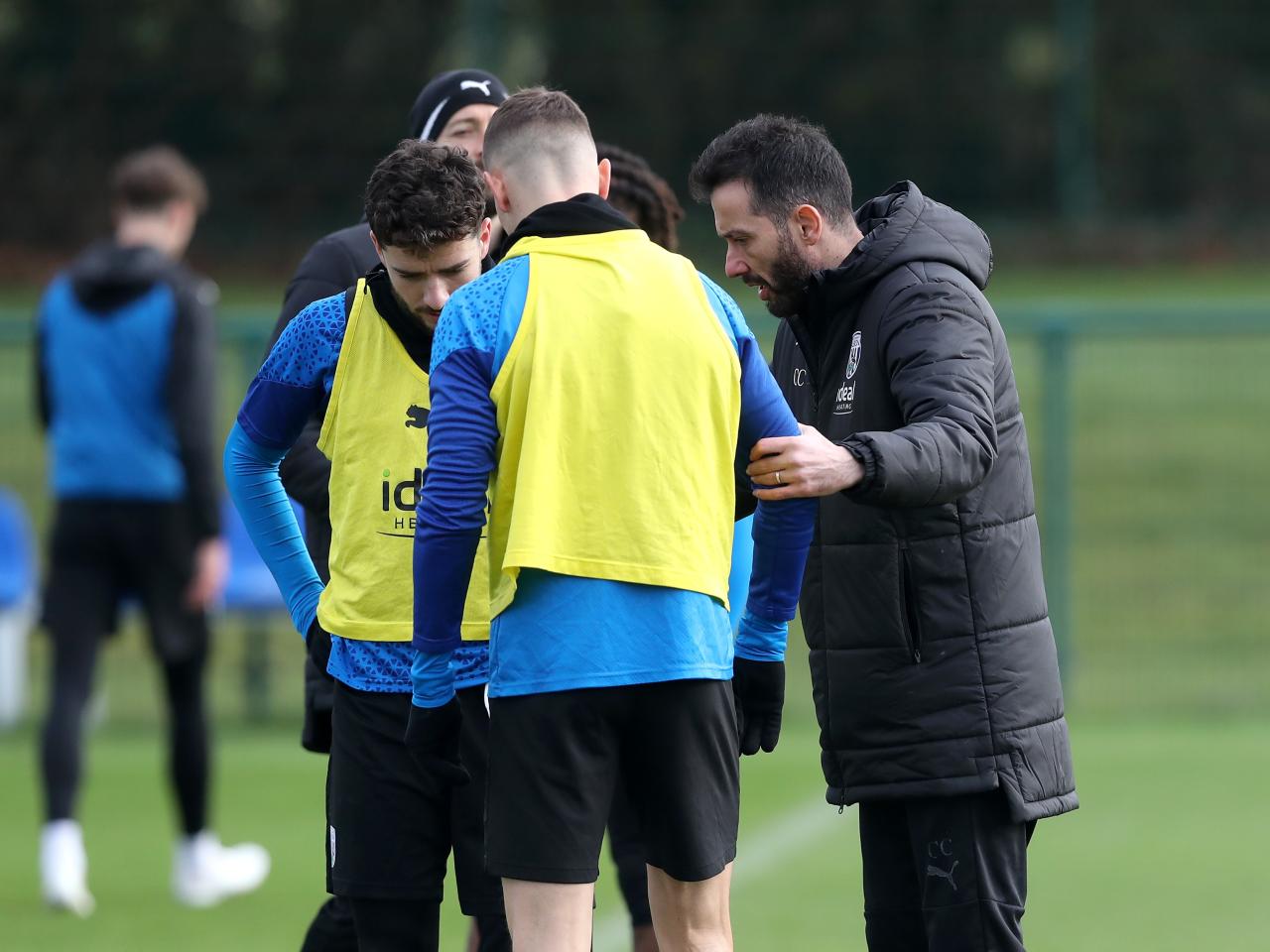 Carlos Corberán talking to Conor Townsend and Mikey Johnston during a training session